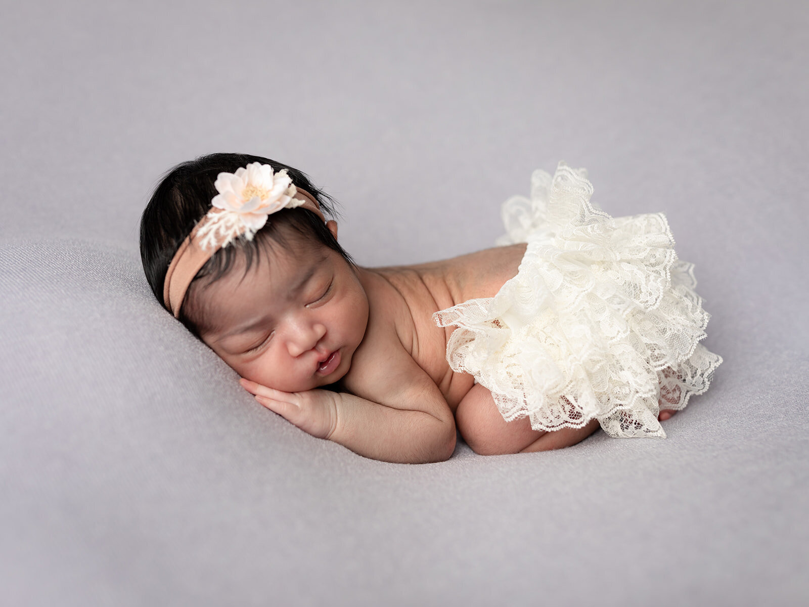 newborn baby girl in white tutu posed for newborn studio portraits cleveland newborn photographer