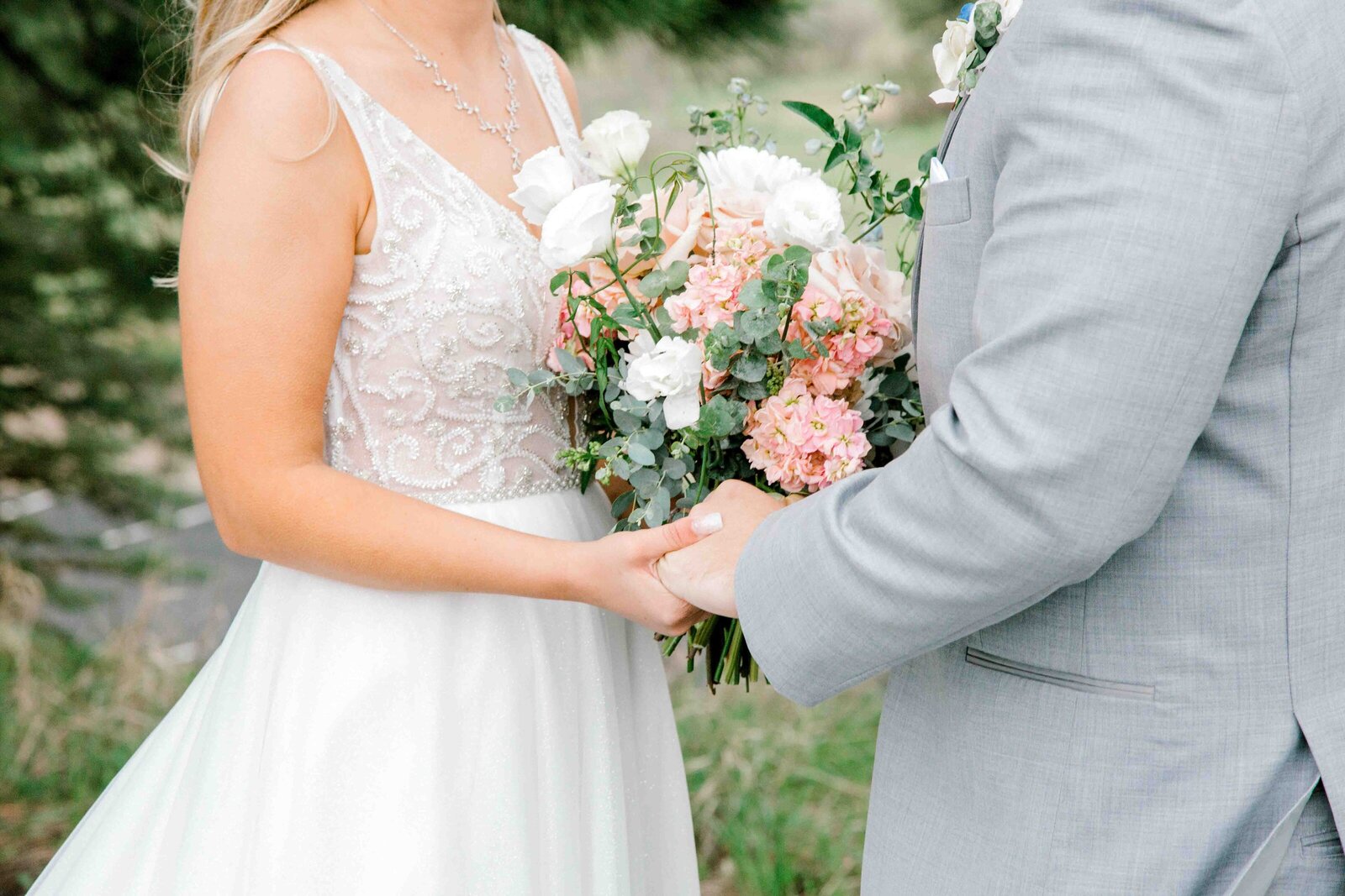 Bride and groom holding each other's hand and floral bouquet