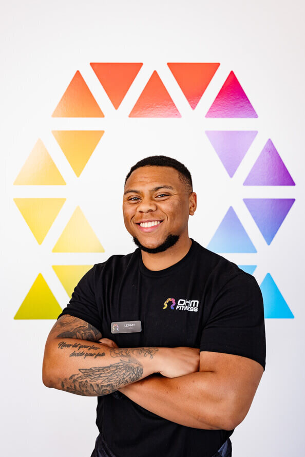 Man folds arms and smiles in front of the OHM logo at his company branding session.
