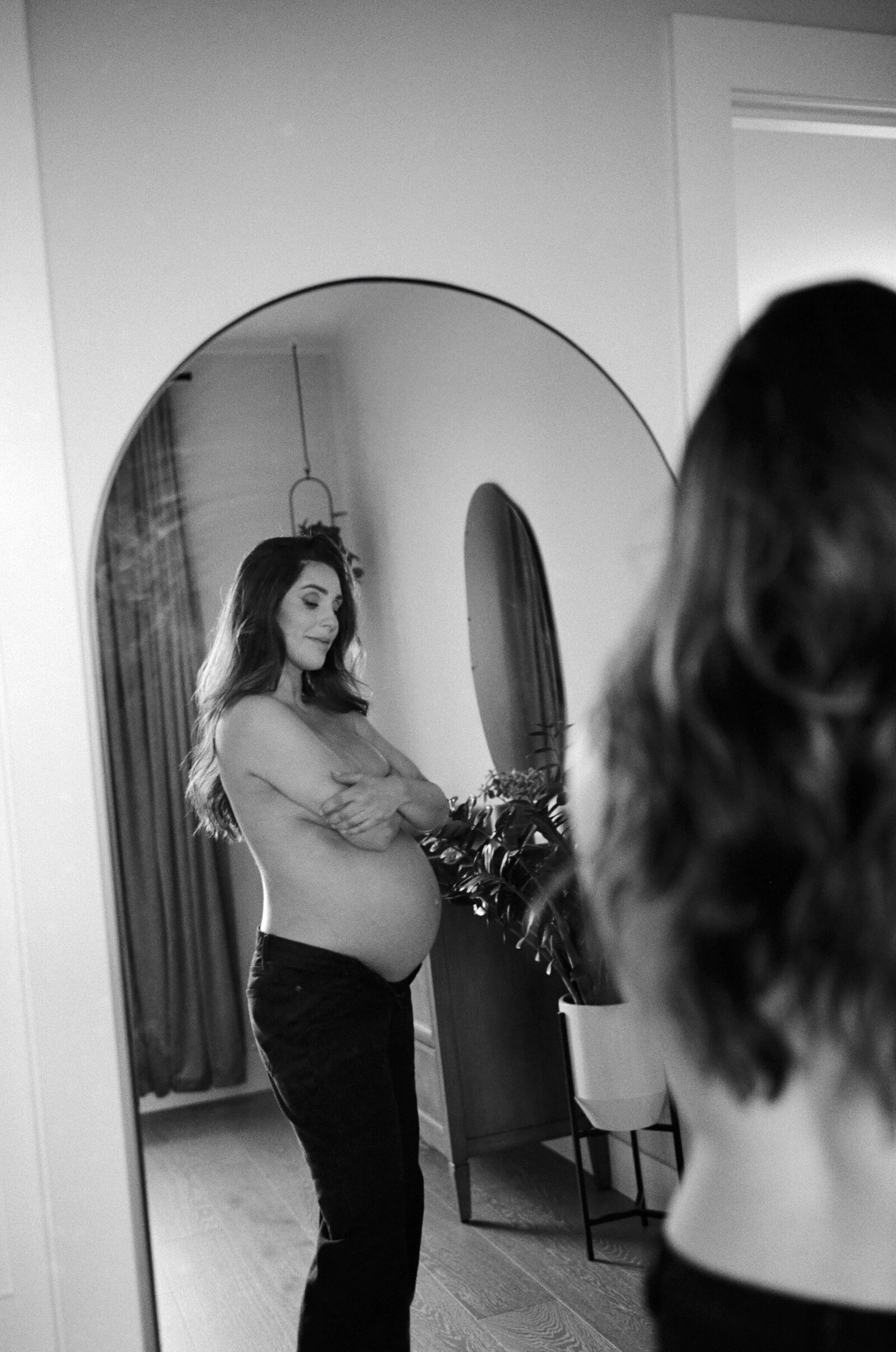 Naked pregnant mother looking at herself in the mirror in her Portland, Oregon home.