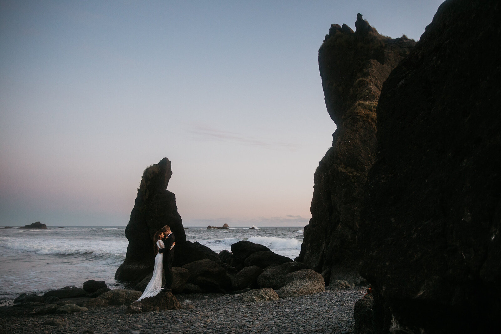 a bride and groom perch on a rock at Ruby Beach during their Washington Elopement