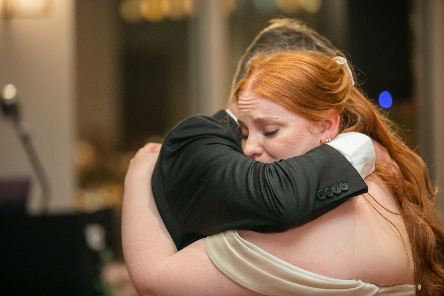 A woman in a white dress is hugging a man in a black suit