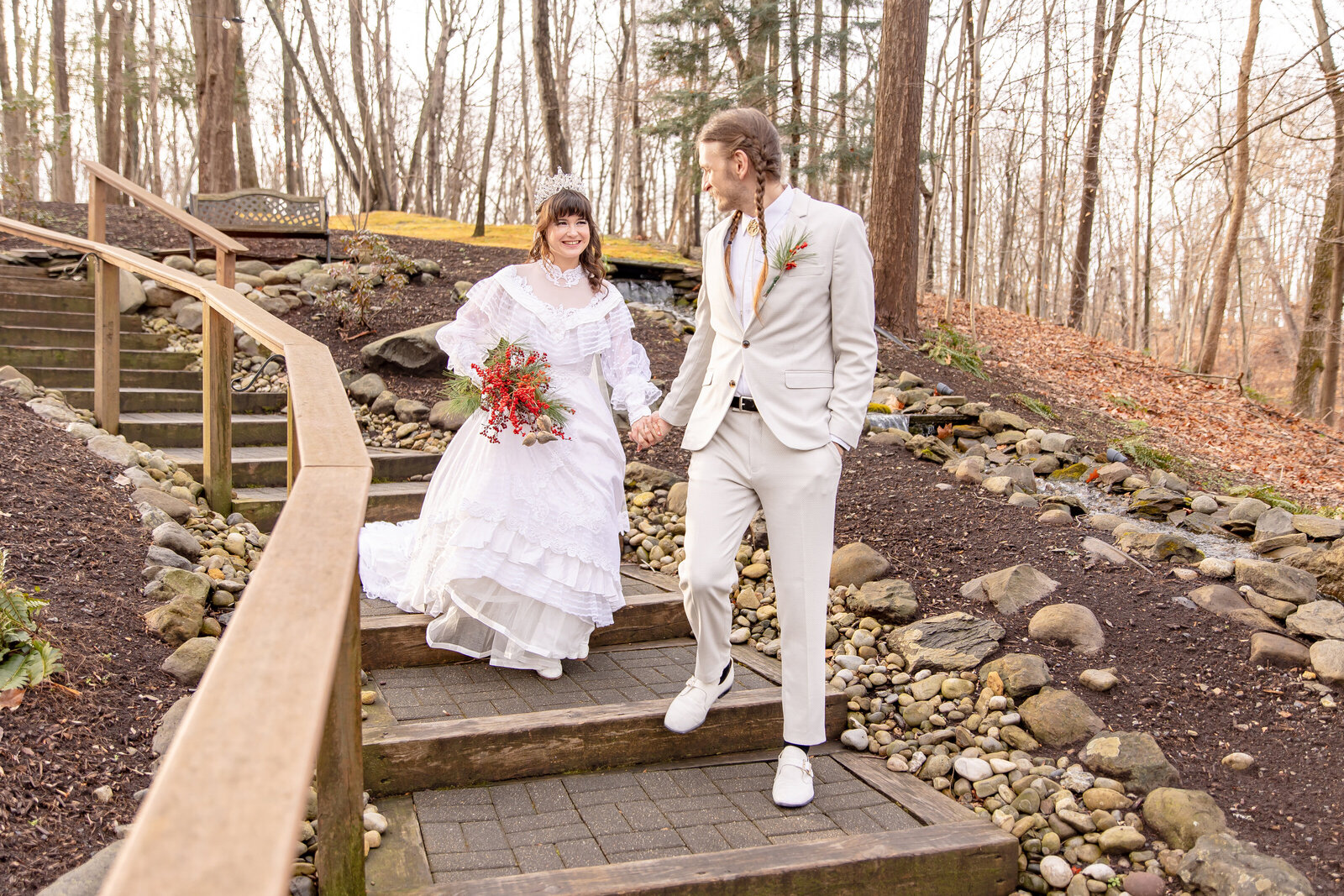 grooms escorting his bride down steps in forest