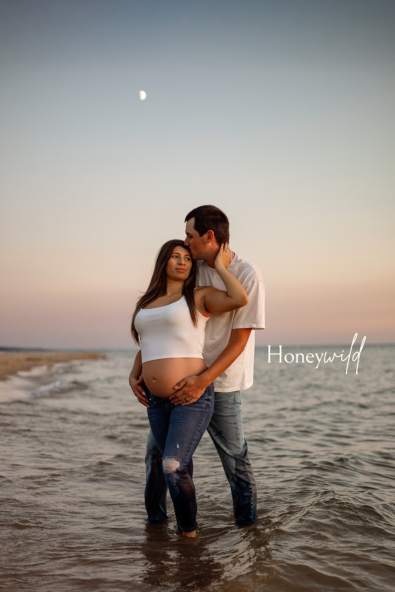 Twin newborns in blue pajamas cuddled together on a navy backdrop during a studio newborn session in Grand Rapids, MI by Honeywild Photography.