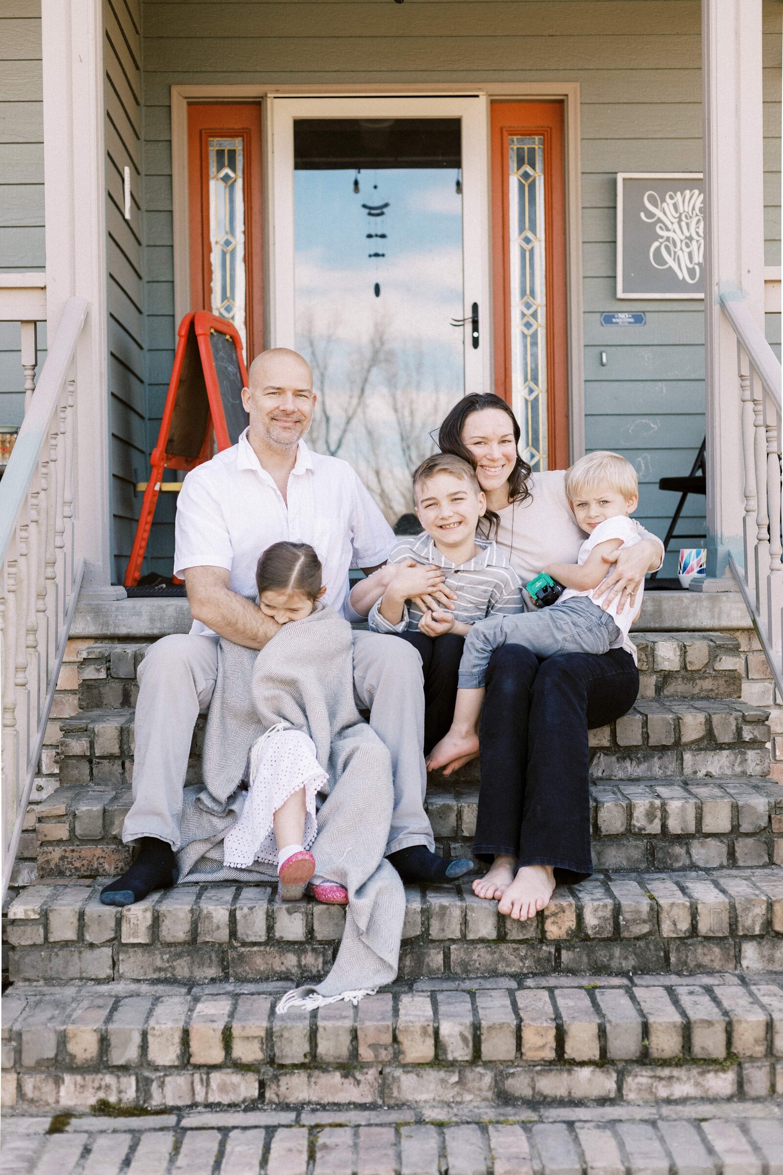 family sitting on front porch steps smiling during peoria illinois family photos 