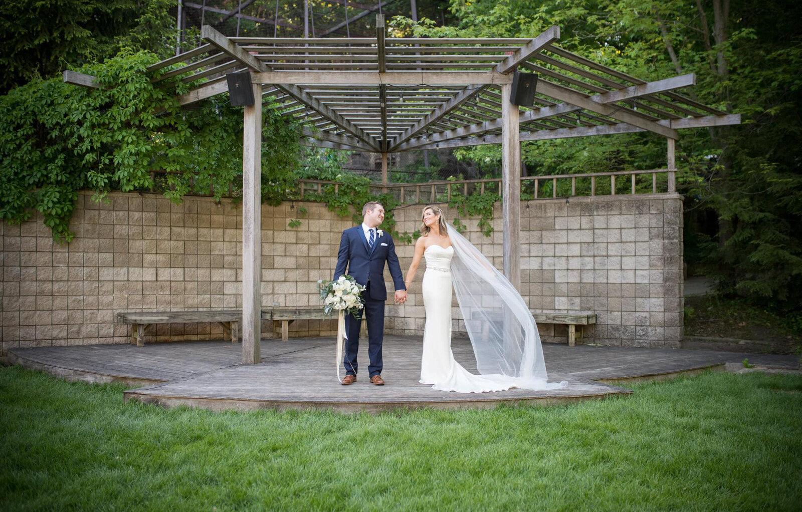 bride and groom on plattform smile as bride's veil billows