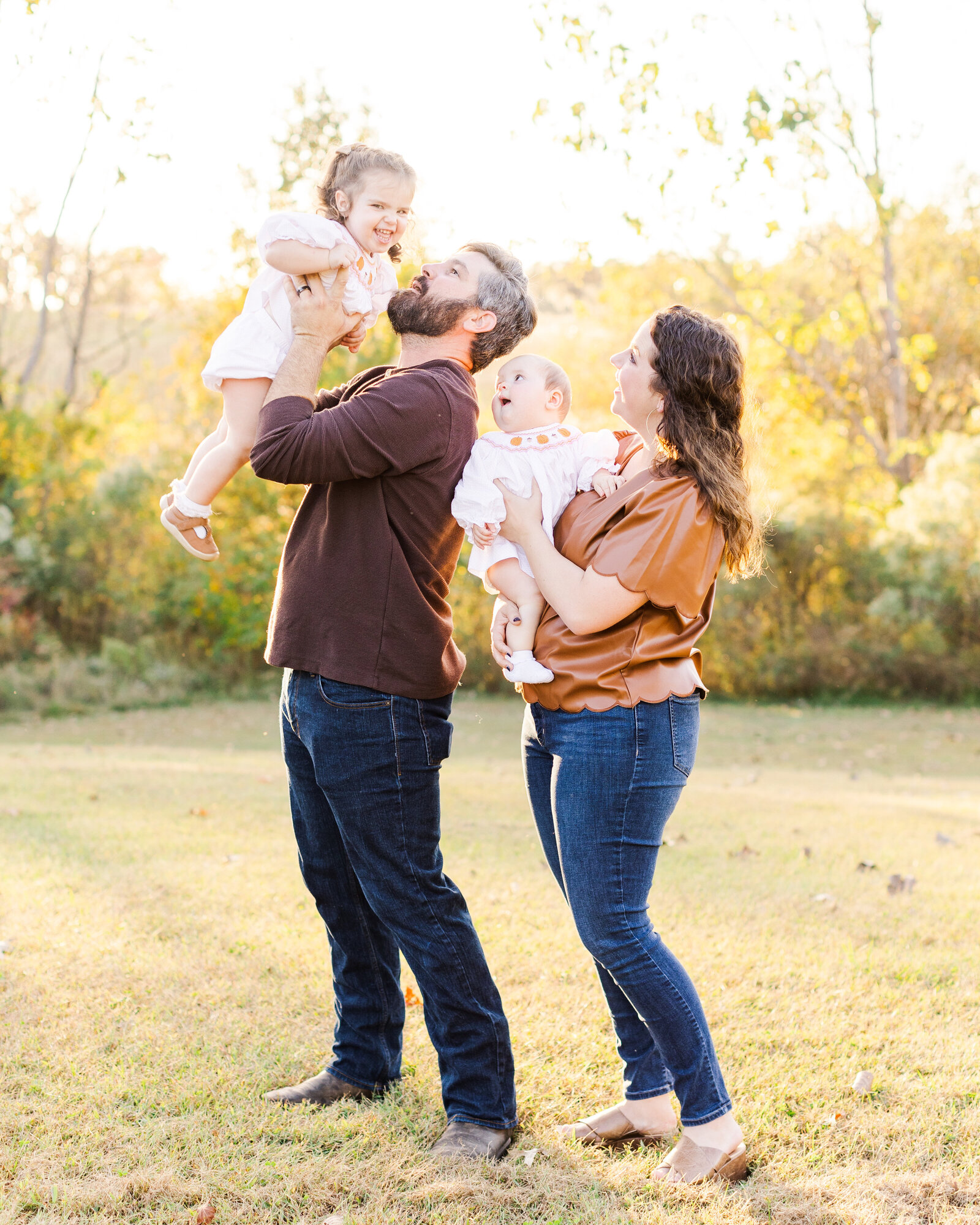 The Taunton family sharing a playful moment with their two daughters during a golden hour mini session, captured by Abby Bell Photography, Fine Art Portrait Photographer based in Alabama.