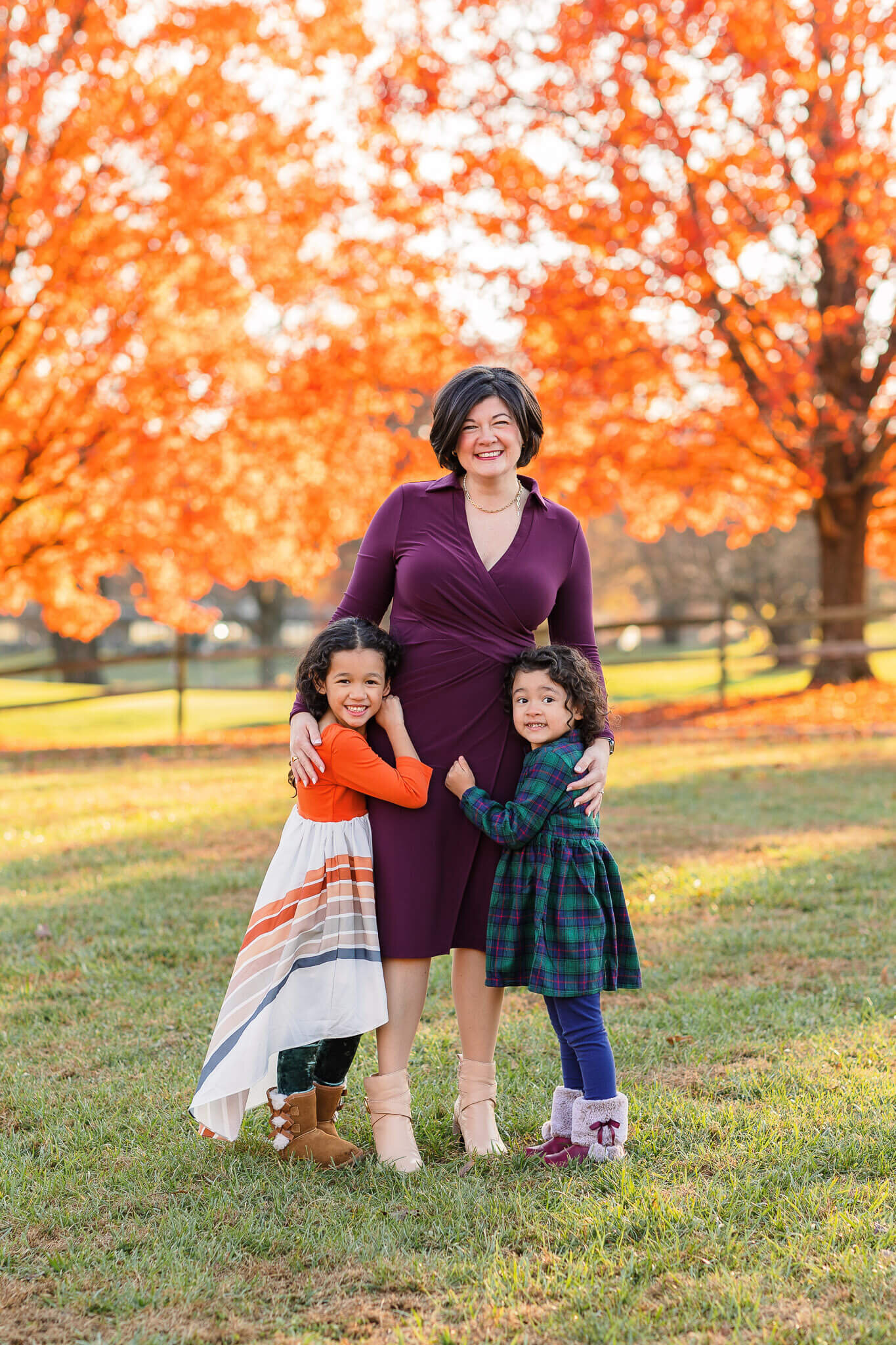 A mom and her two daughters standing in front of orange trees