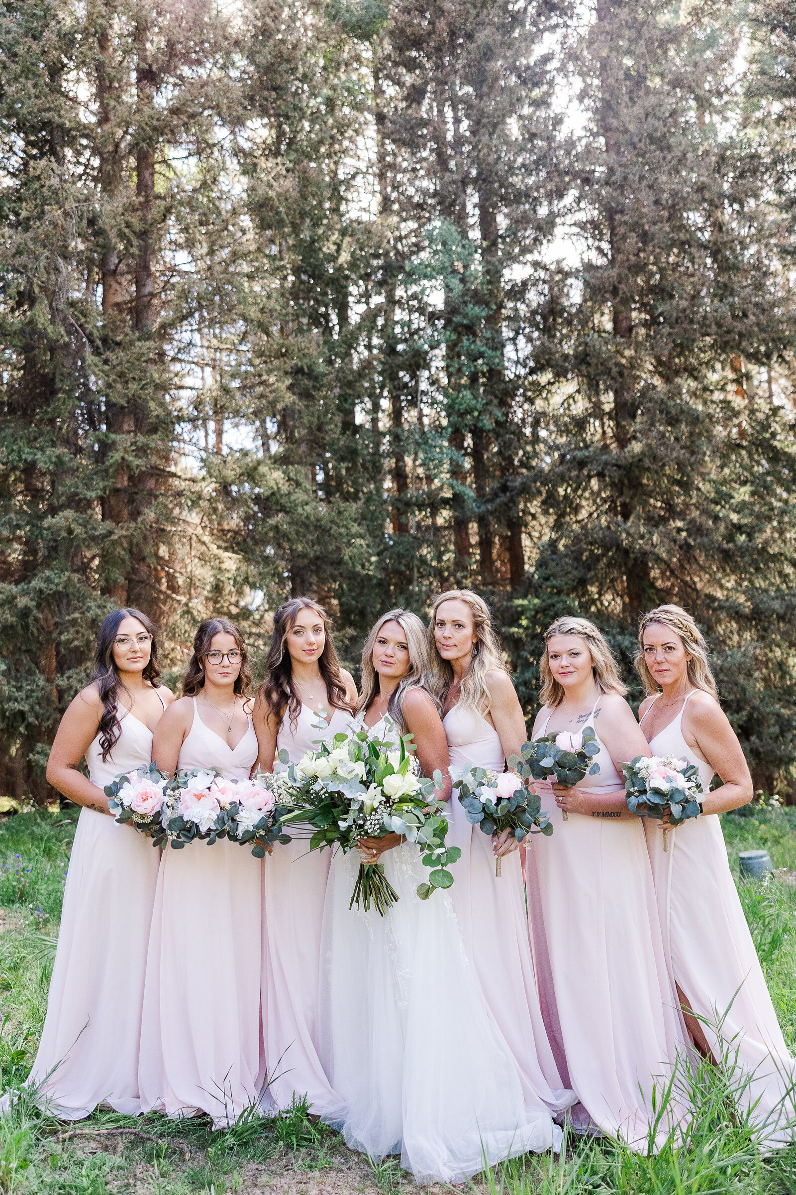 All bridesmaids with brides lined up for photo holding bouquets