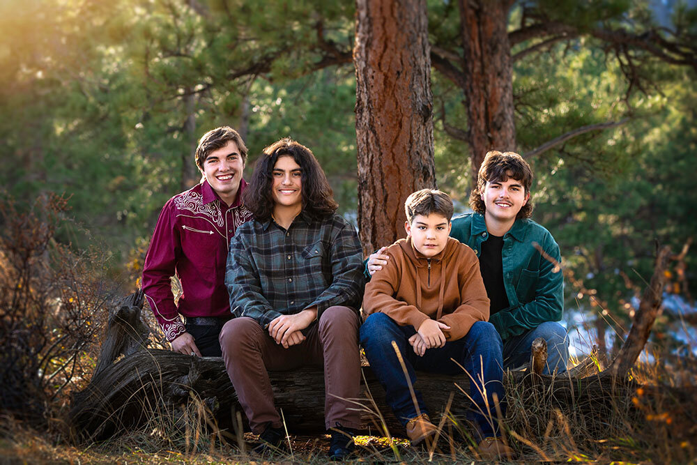 4-teenage-boys-outdoor-family-picture-mountain-forest-green-pine-trees-sitting-on-log