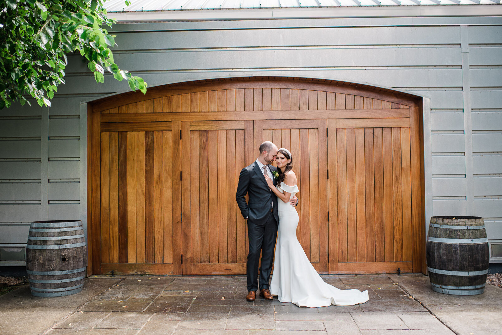 bride and groom standing in front of large wooden door to winery