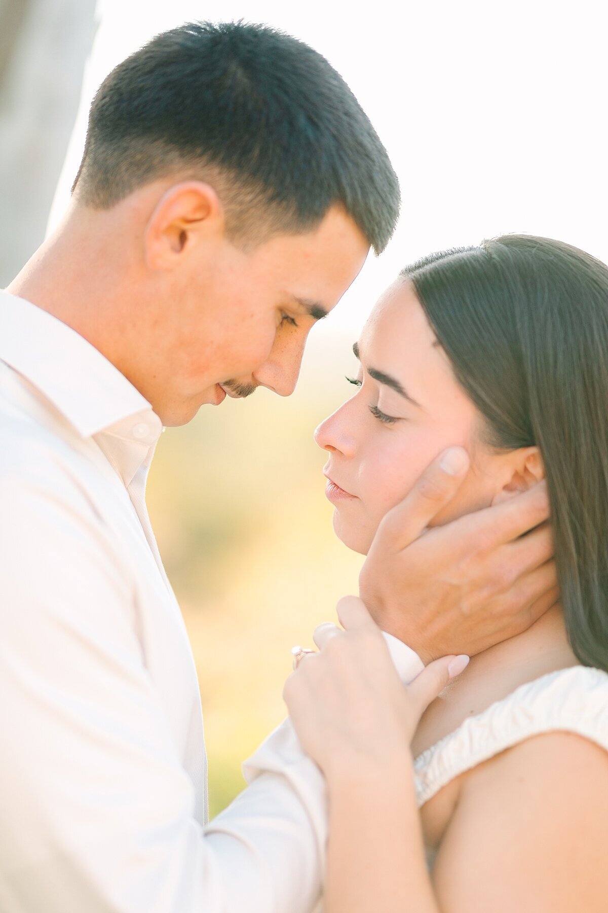 Groom holding the bride's face during their engagement photoshoot at Alta Vista Botanical Gardens in Vista, CA.