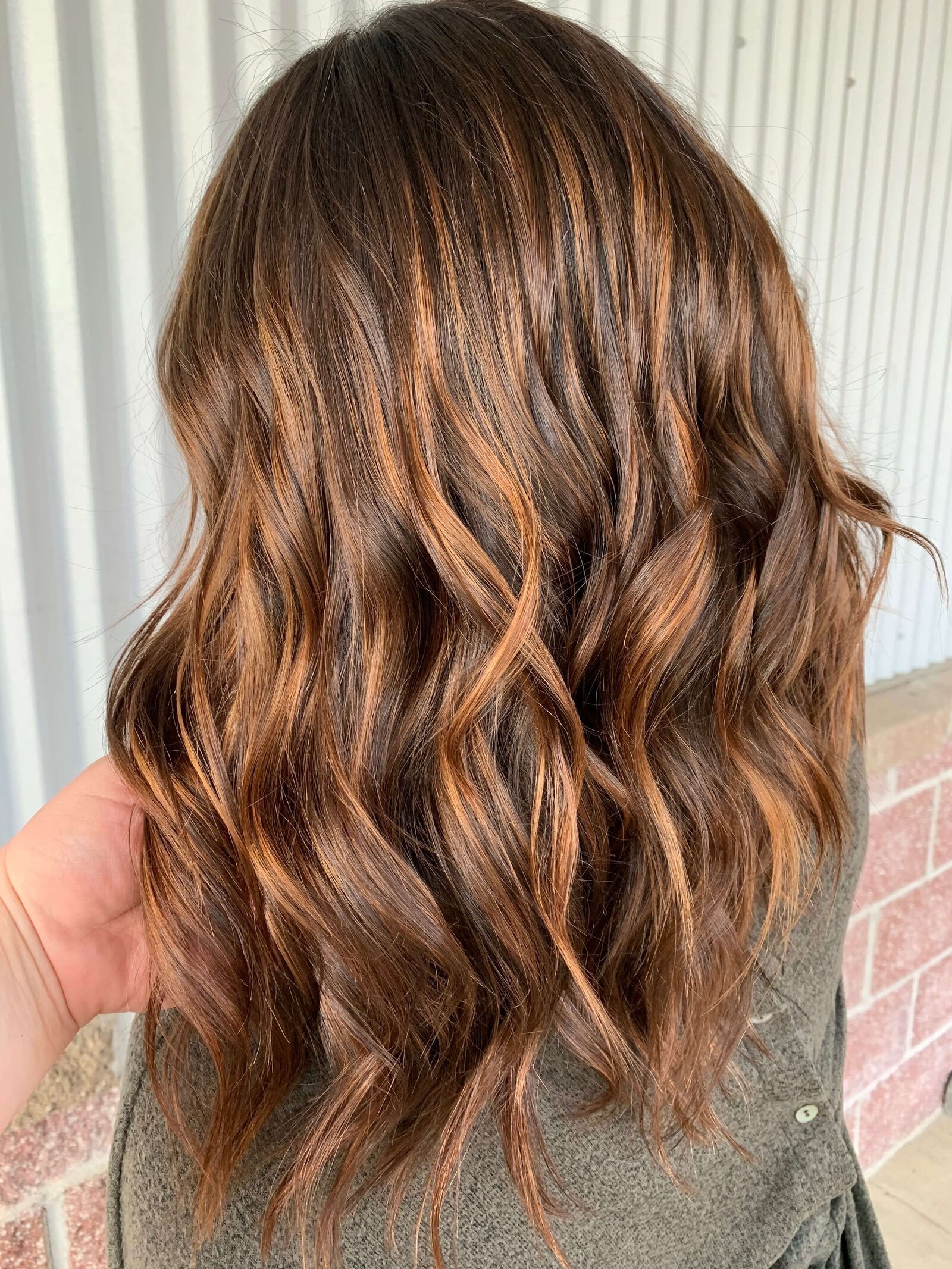 Dimensional brunette with soft waves—representing custom color and lived-in looks at Maven + Grace.”