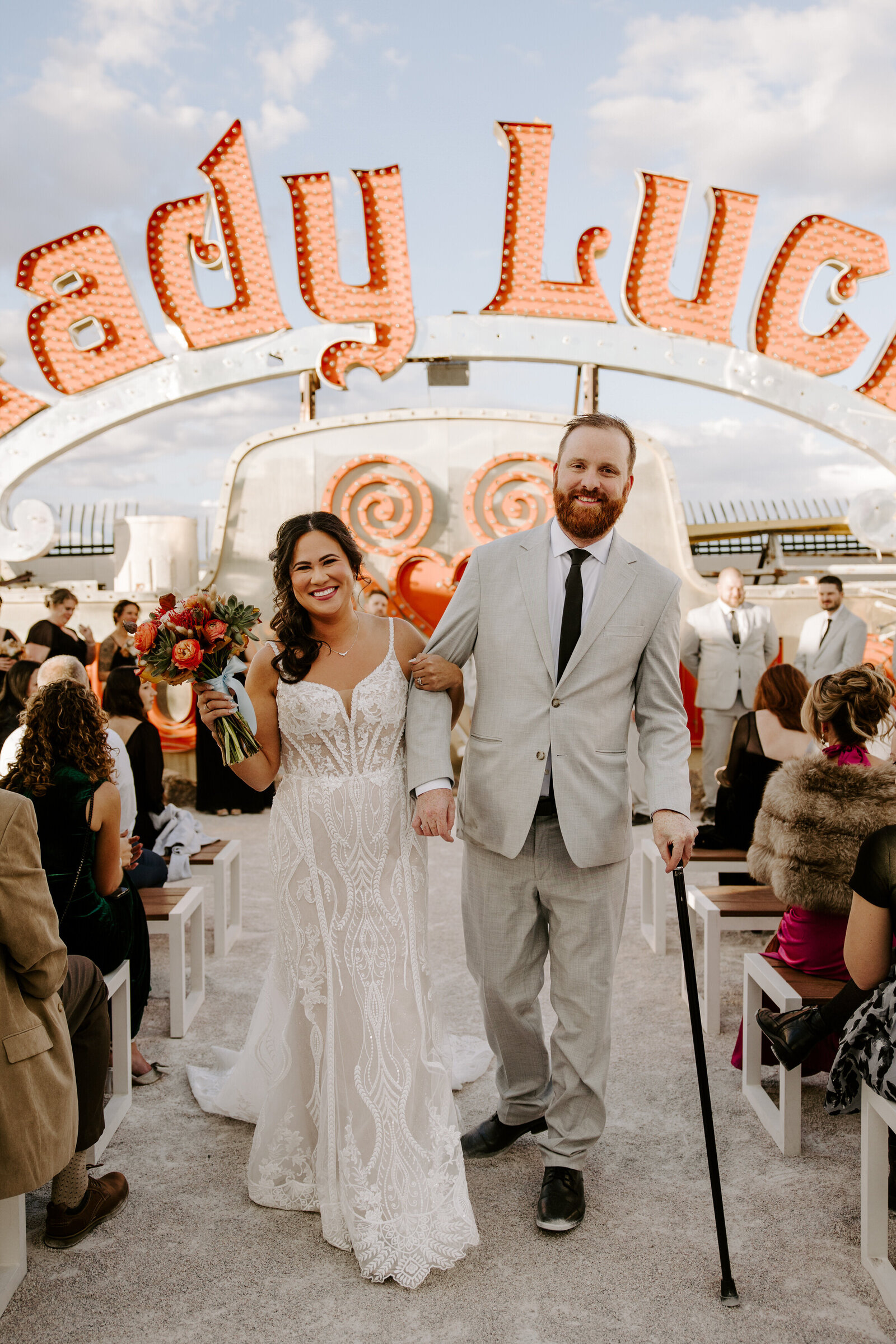 A couple holding hands and smiling as they walk back up the aisle after their wedding 