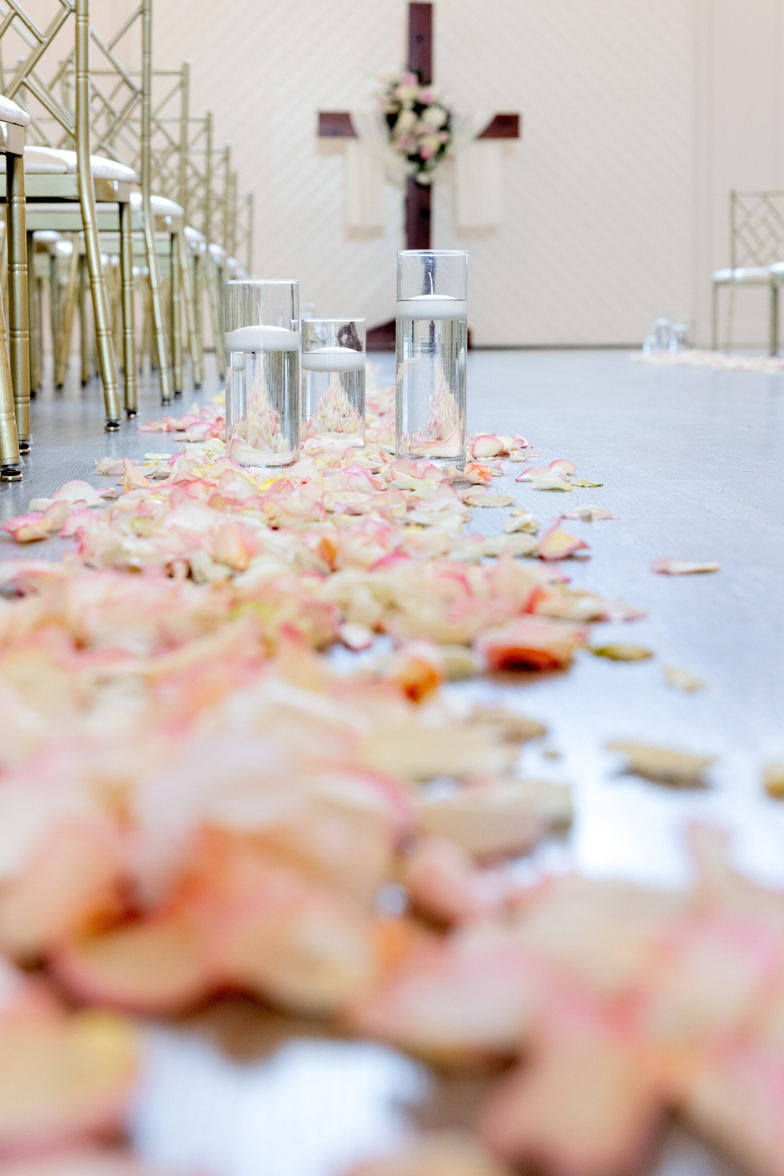 wedding aisle with pink petals and cross in the background