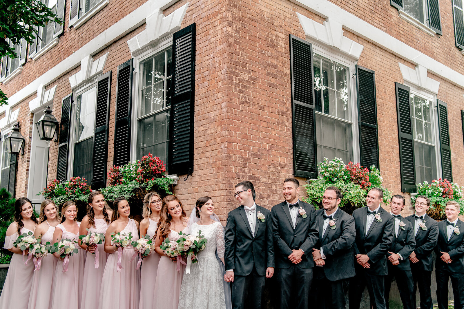 A wedding party peeking around the corner of a building during a Catholic wedding in Northern Virginia