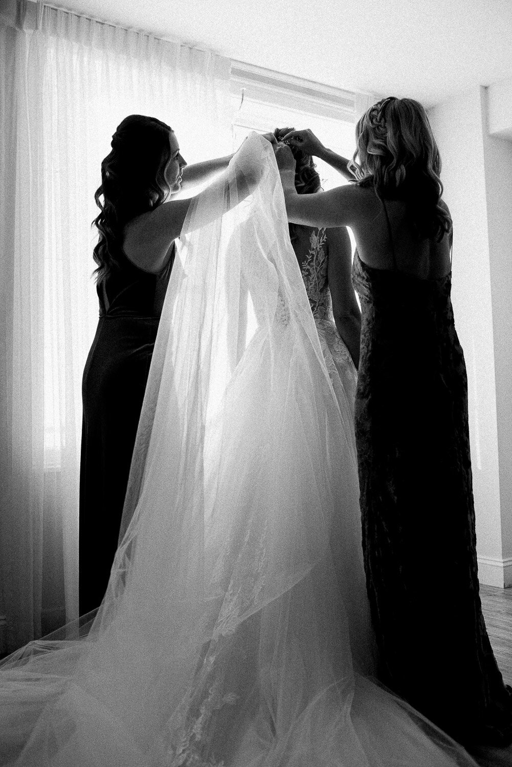 bridesmaids help bride with veil