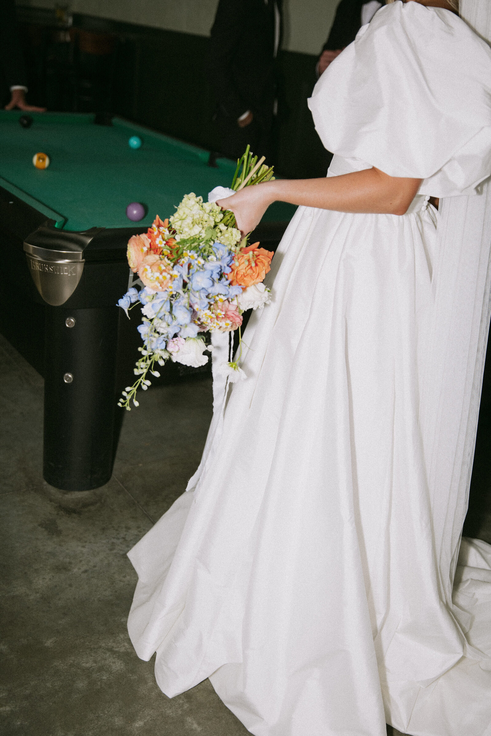 Bride holding bouquet while playing billiards at The Royal in Boise