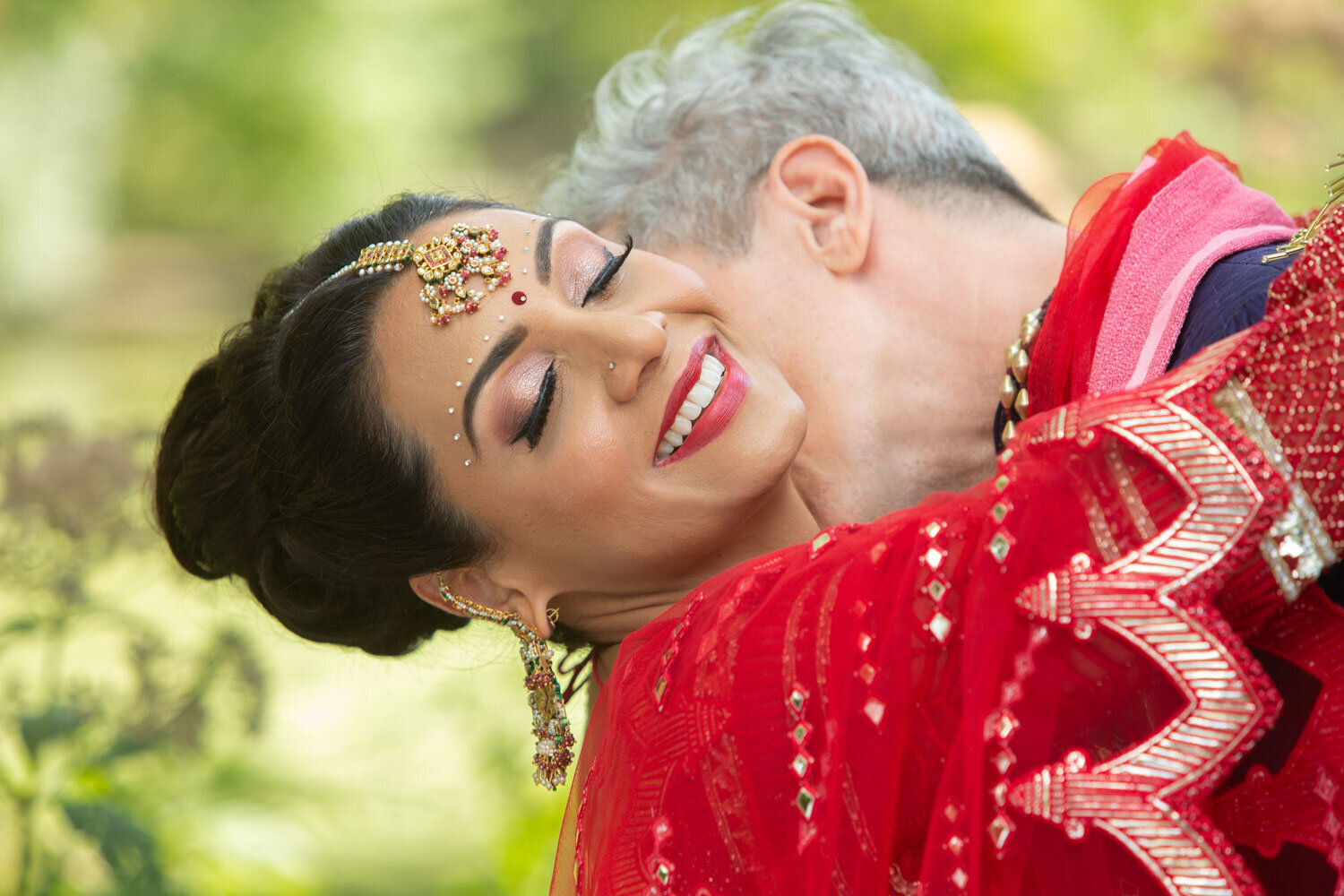 A woman in a red dress is kissing a man on the cheek.