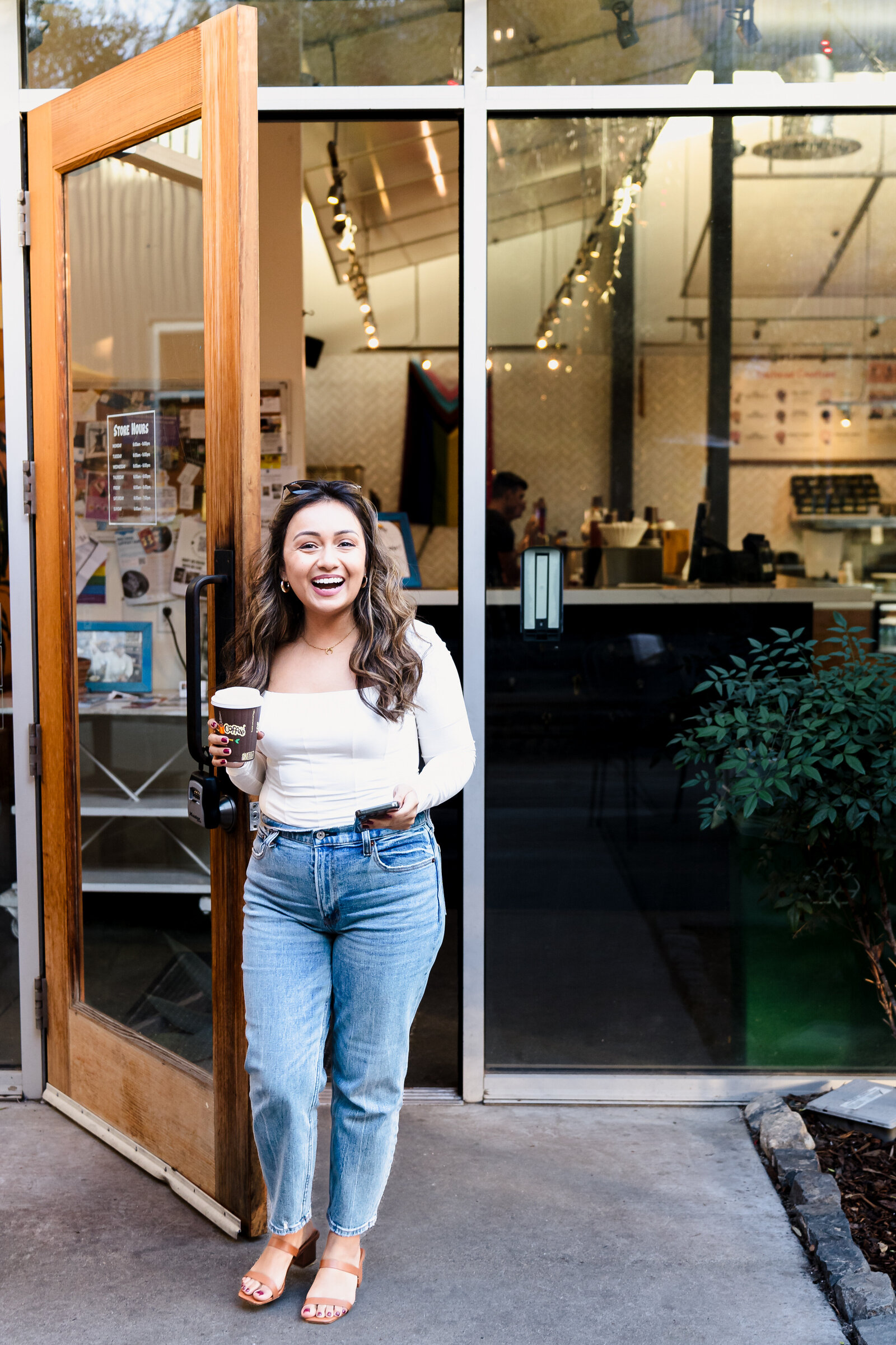 woman getting out of a coffee shop, coffee  on  hand