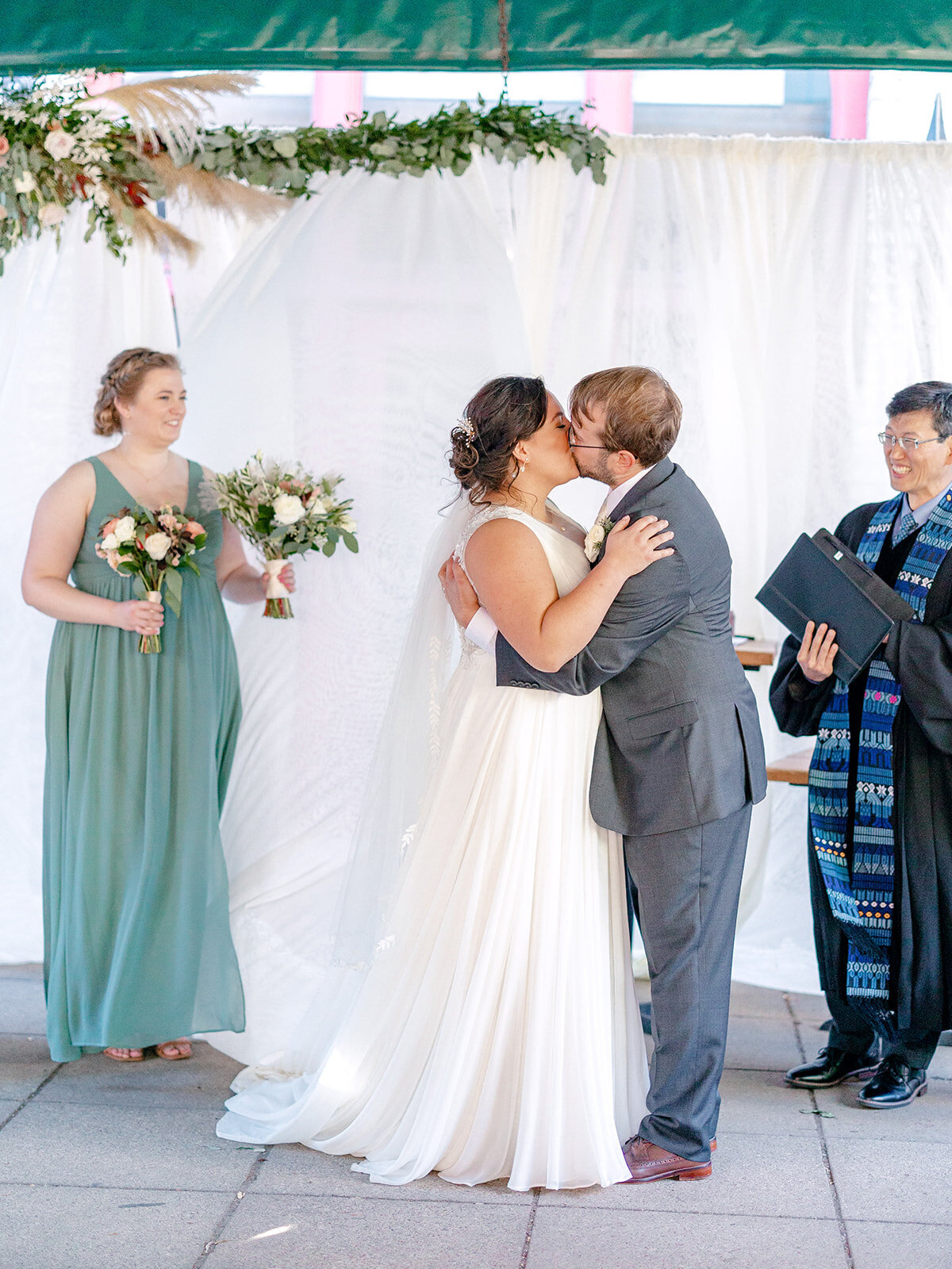 bride-groom-ceremony-kiss-white-backdrop