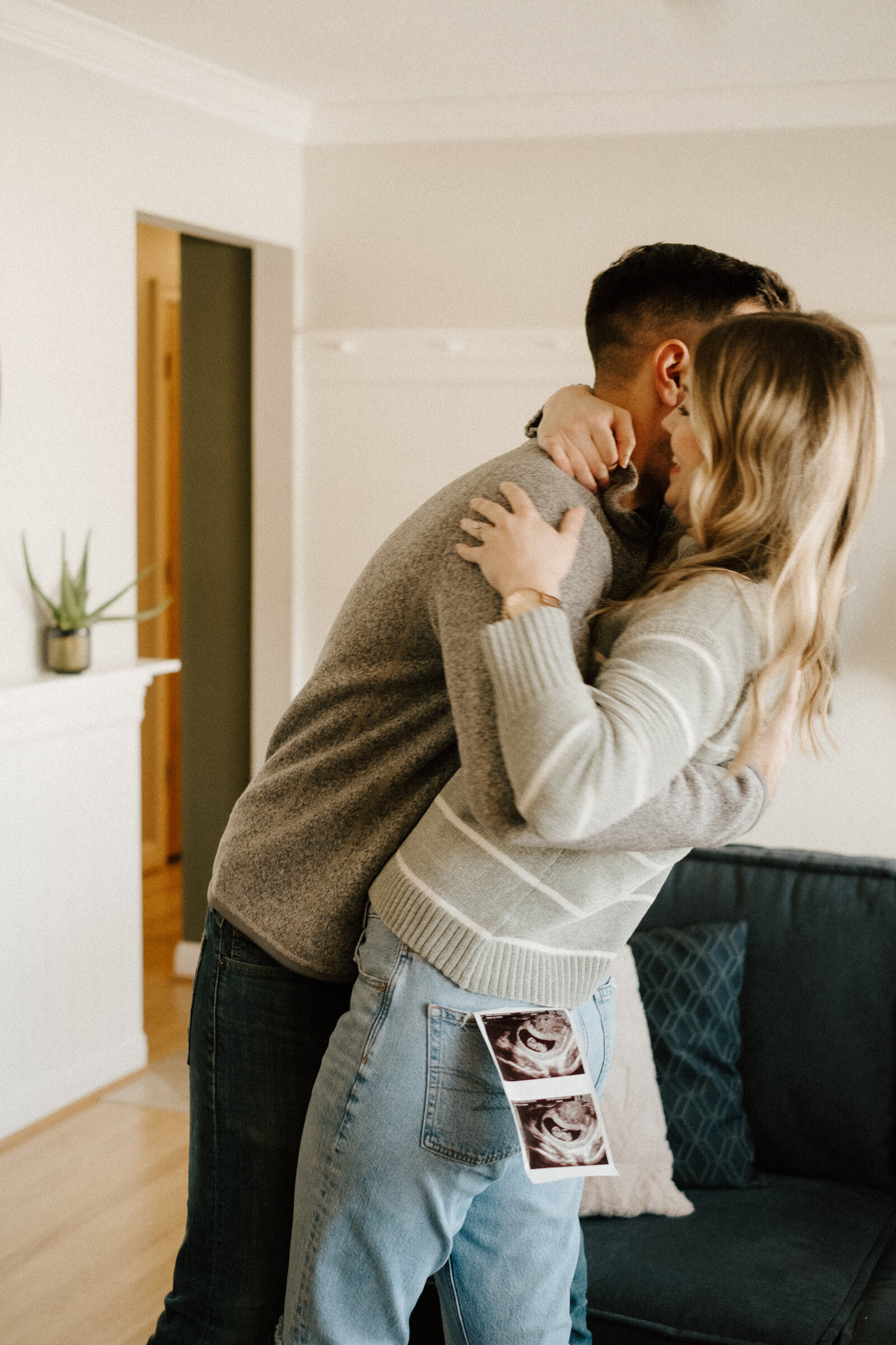 A couple dancing  in their living room during their in-home pregnancy announcement photoshoot with Stacey Vandas Photography.