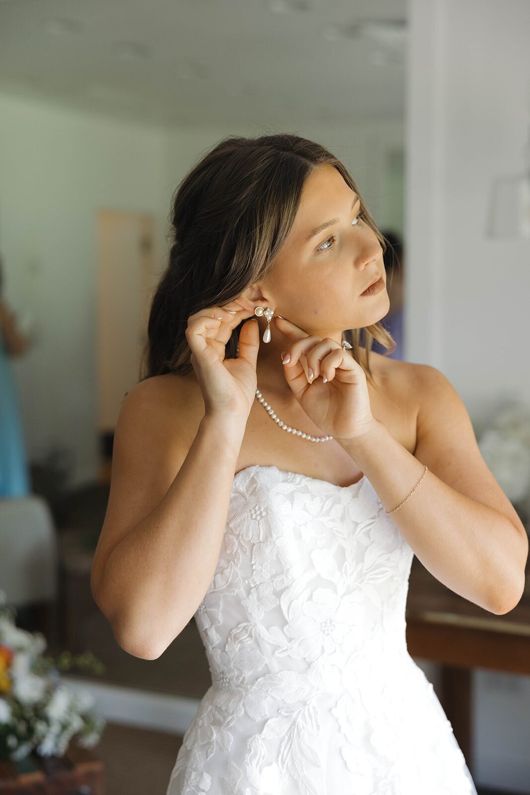 Bride putting on her earrings in her wedding dress
