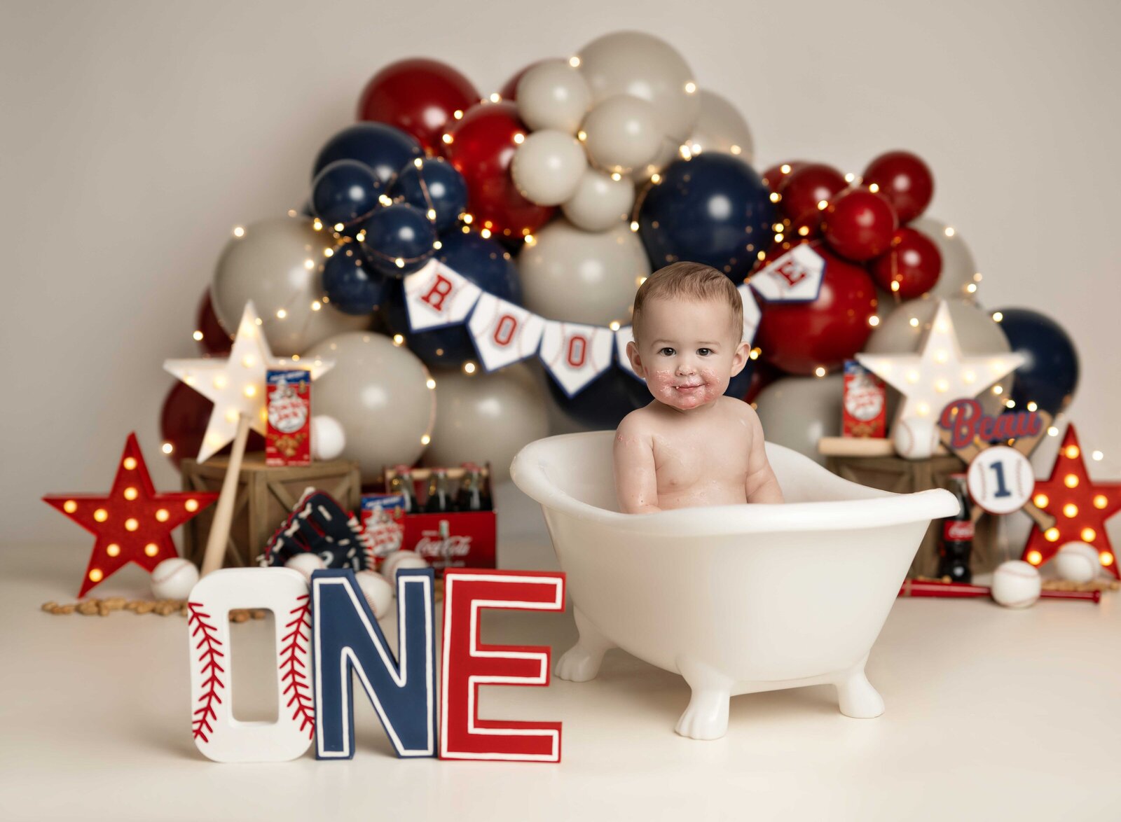 baseball theme cake smash set with baby boy playing in bath tub after cake smash mess. Studio cake smash photo taken by Jenni Nikki Photography in Atlanta, GA.