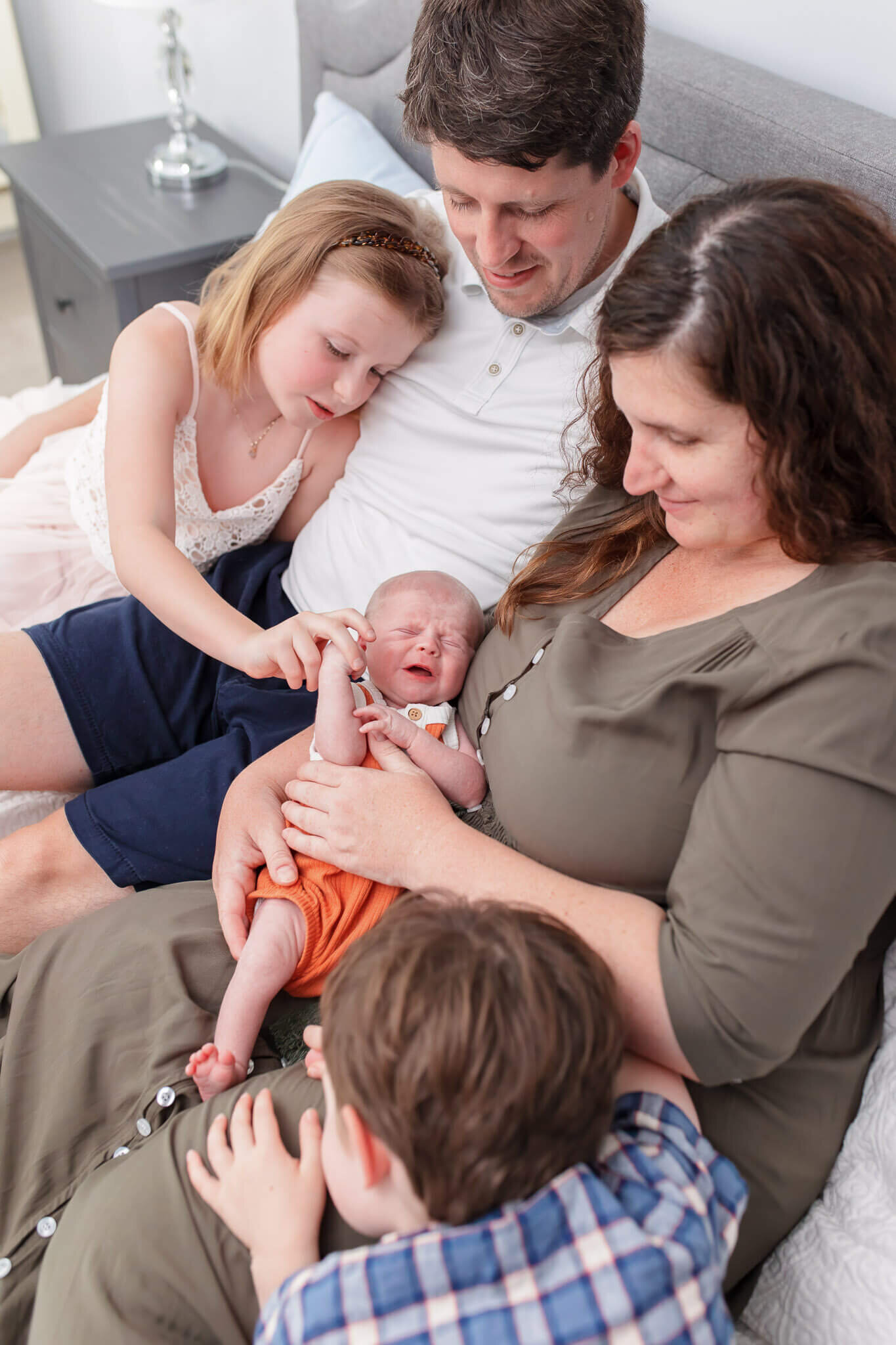 A family of five snuggling in bed.
