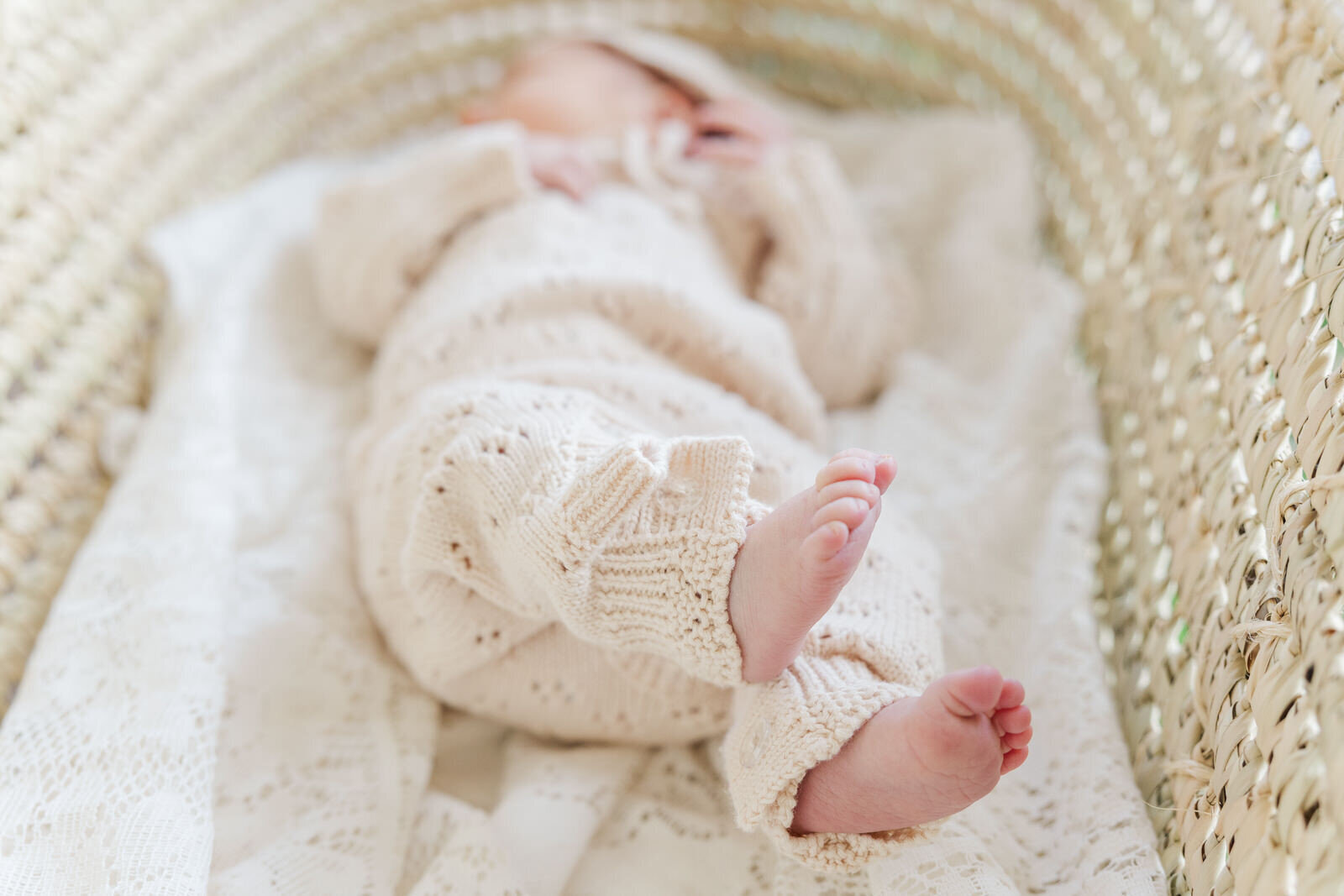 Newborn lays in moses basket showing feet close to camera