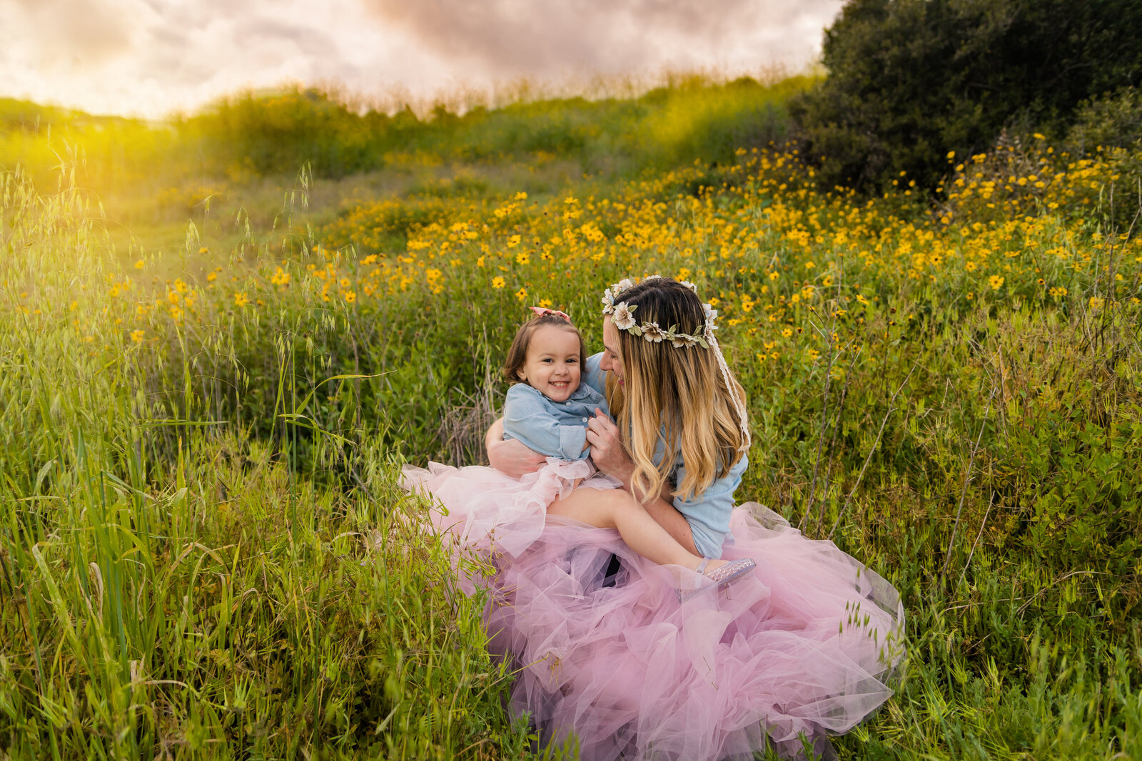 Family Photographer, a mother squeezes her daughter in a field of wild flowers