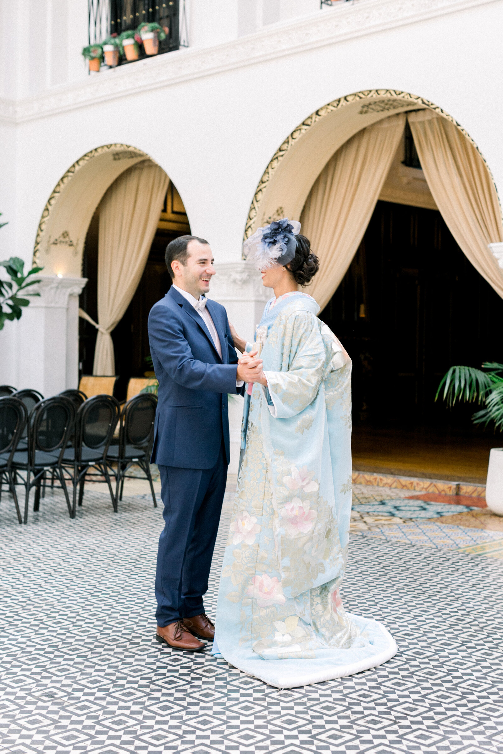 Couple dancing in the tiled courtyard as the bride wears a pastel blue wedding kimono at The Ebell Club Long Beach, available for kimono rental in Los Angeles | ロサンゼルスThe Ebell Club Long Beachのタイル張り中庭で淡いブルーの花嫁着物レンタルを着て踊る二人
