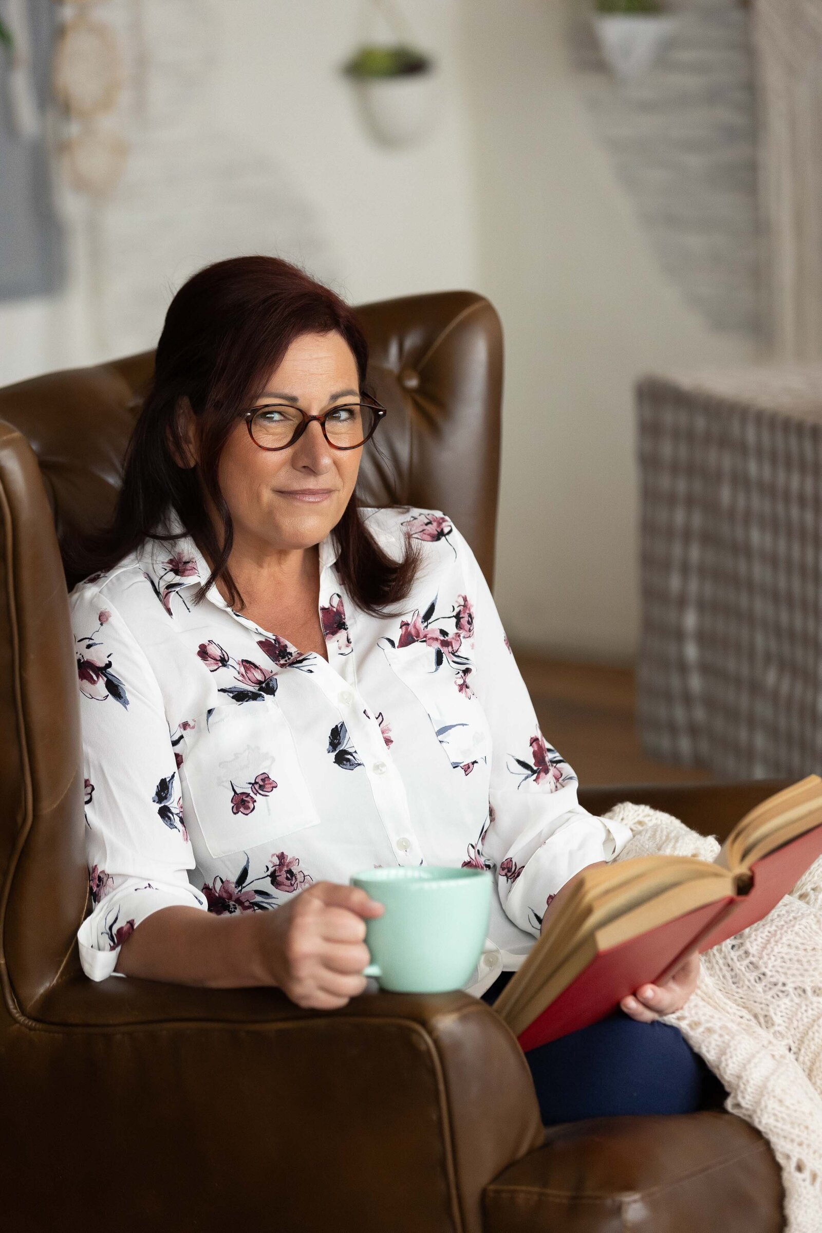woman reading a book while holding a mug