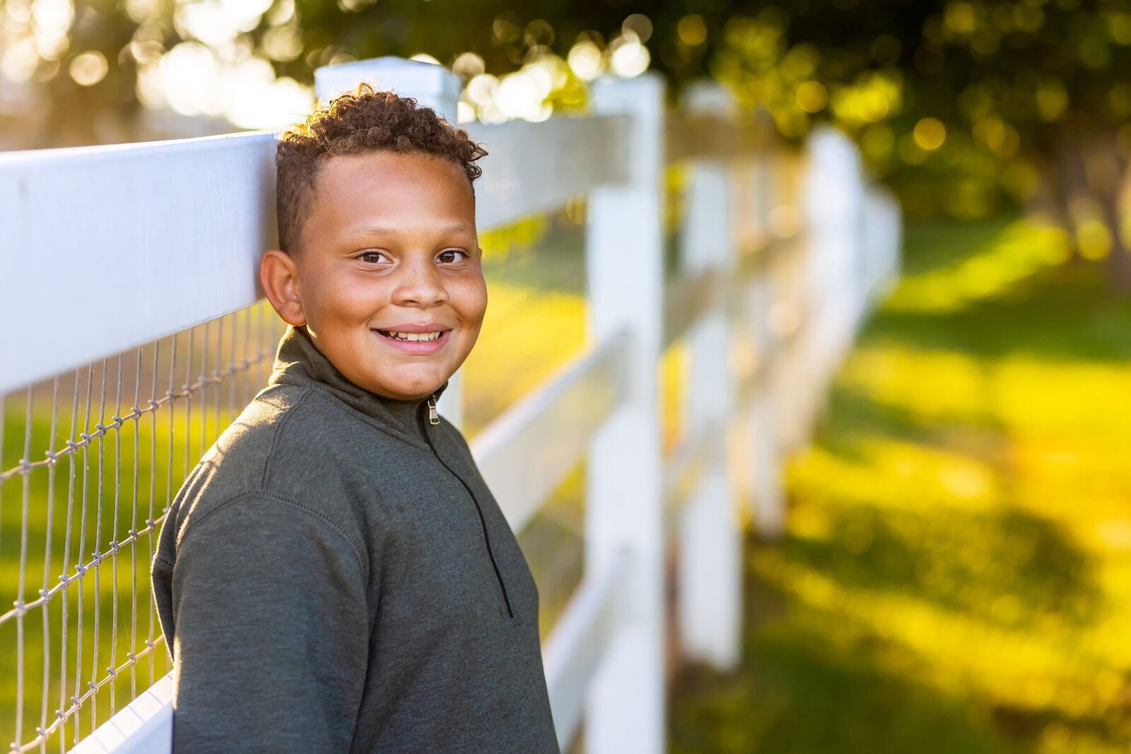 teen boy leaning on a fence