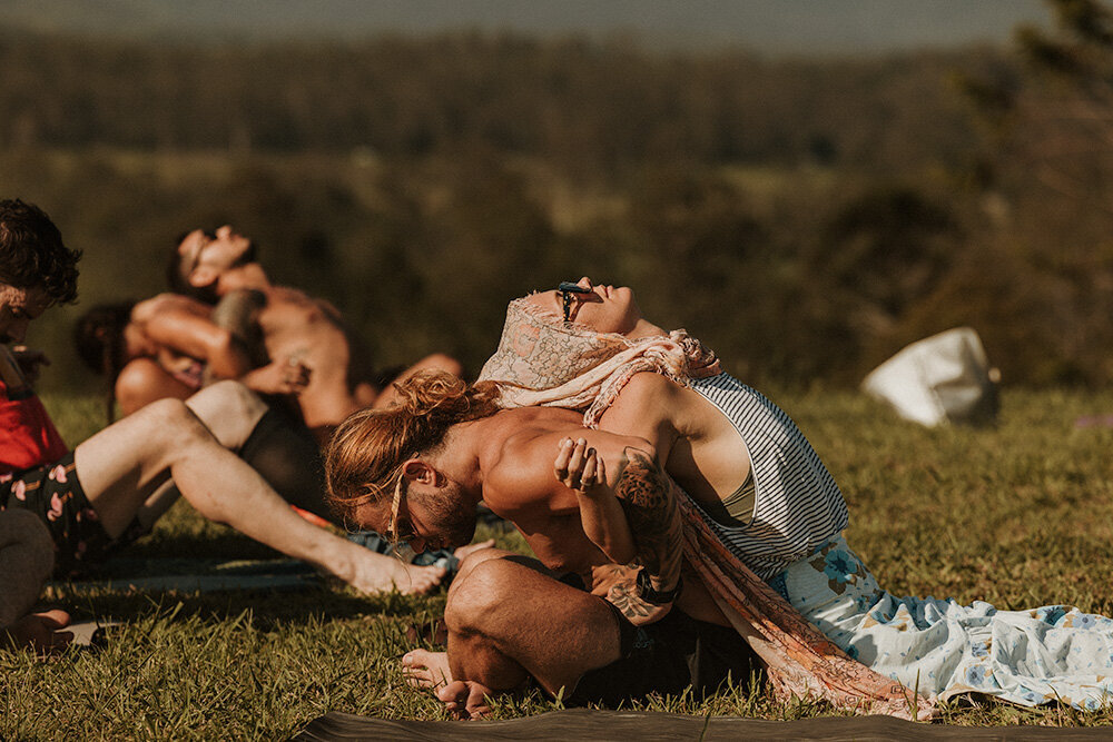 Group of people embracing on a grassy field during a relaxed outdoor retreat captured by Sunshine Coast event photographer.