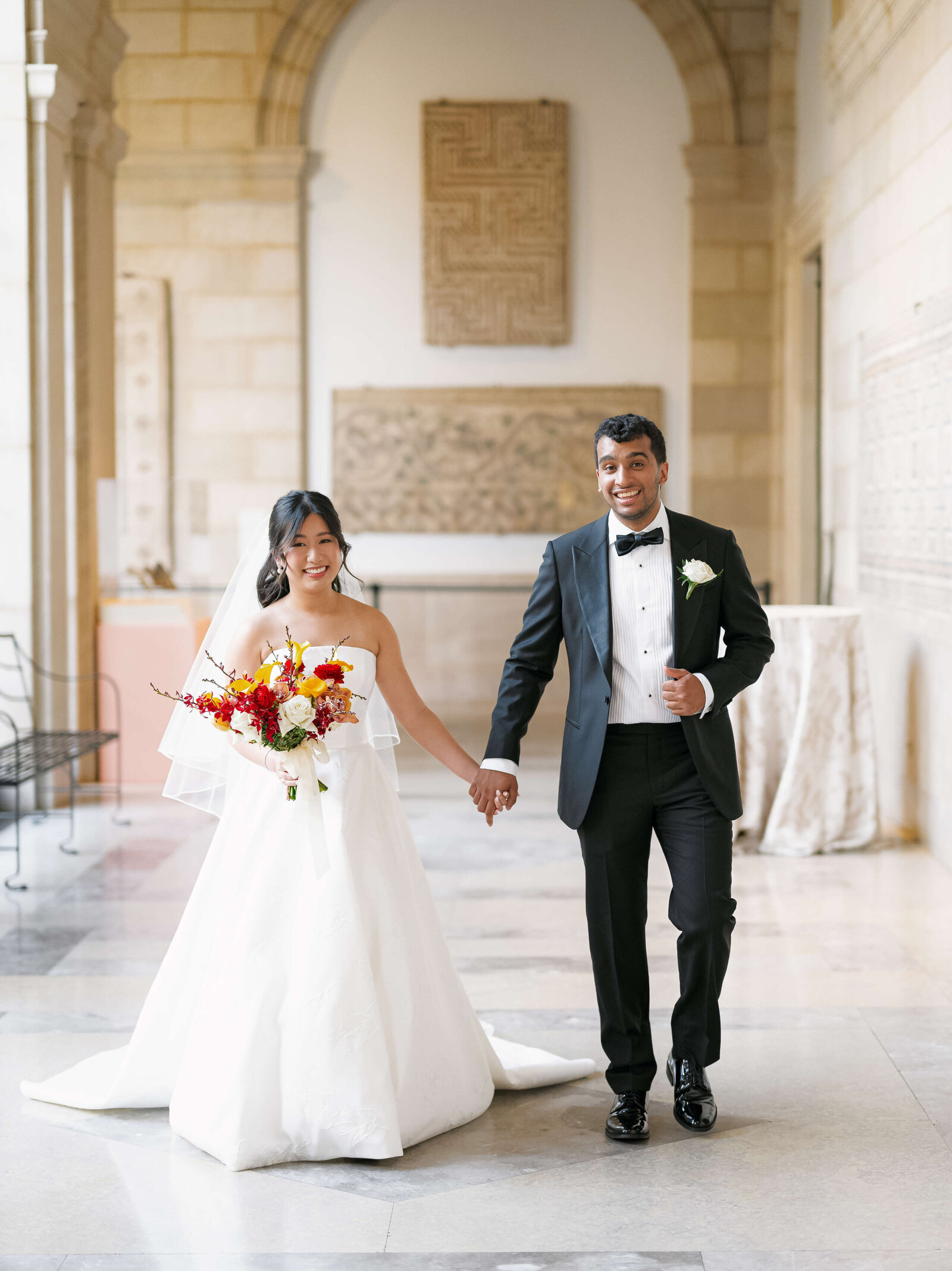 A groom and his bride walk down a hallway together after their wedding