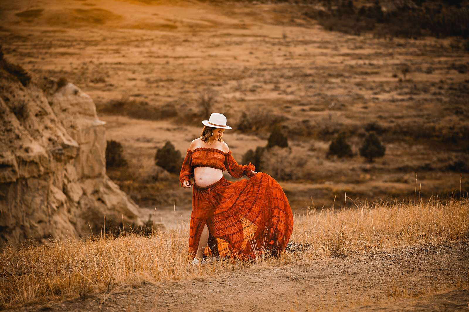 While show a little fun and flirty side of herself, a momma enjoys the vast prairies and the fire dancing in the sky during her maternity photoshoot near Medora, ND