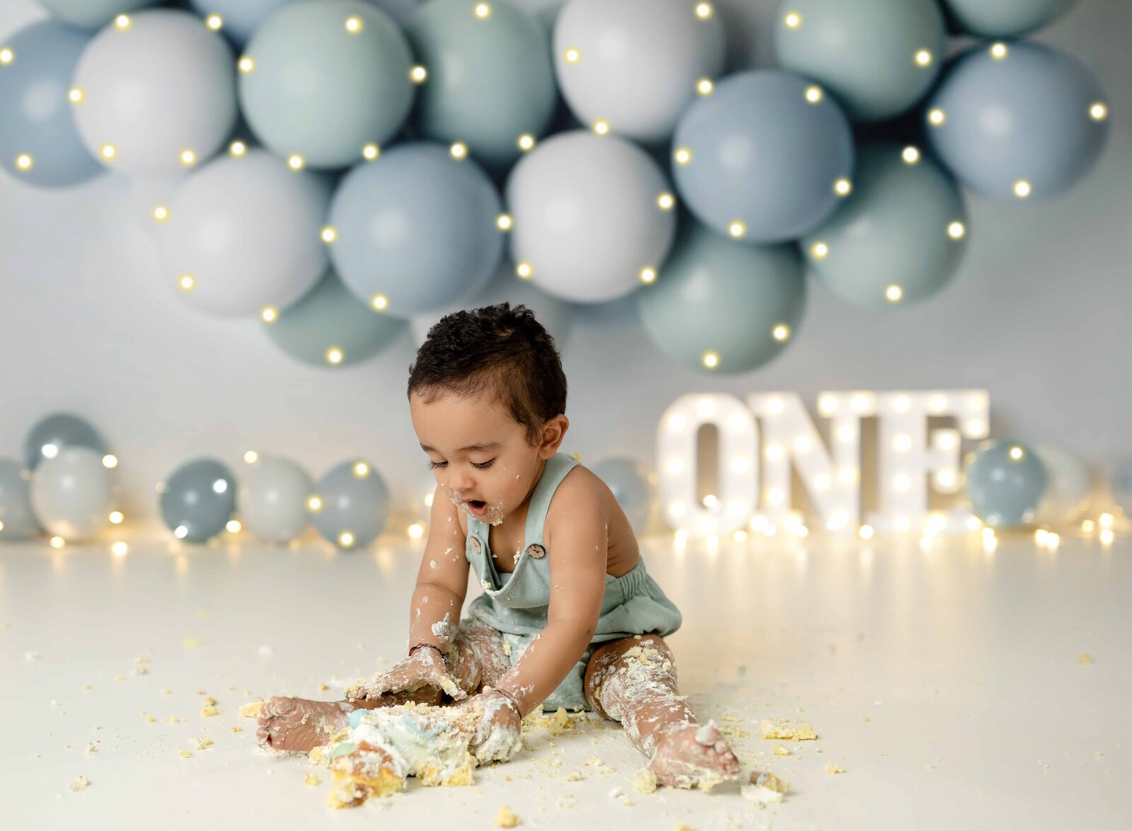 Baby taking 1st birthday photos and smashing a cake to the ground.