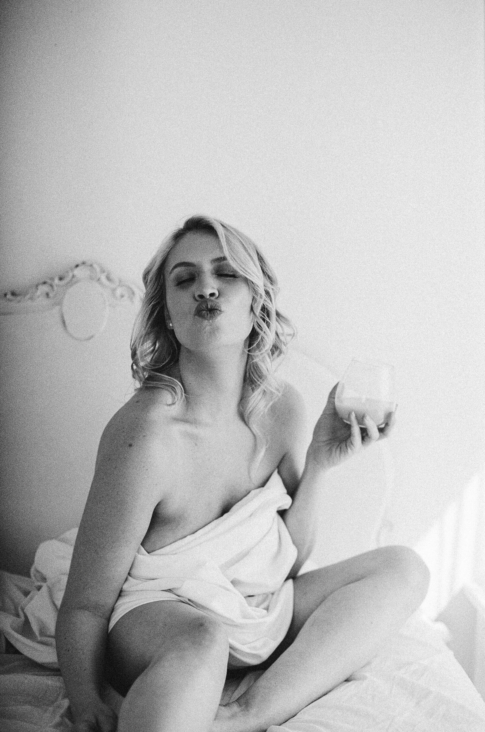 Black and white boudoir photo of a woman kissing at the camera