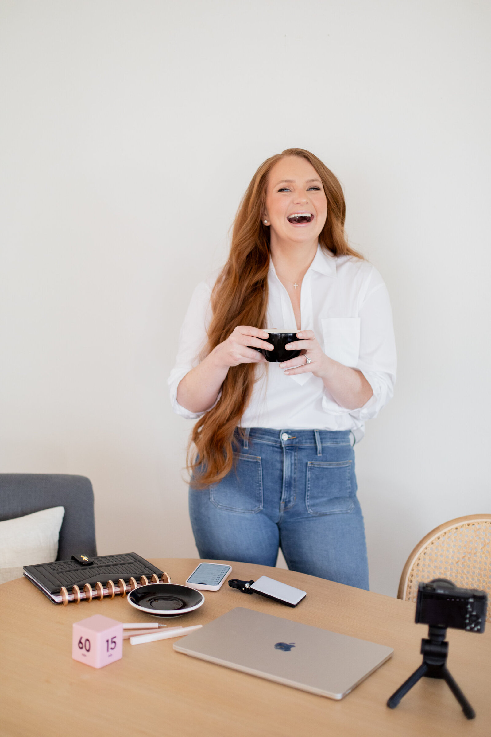 Kristina laughing, holding a coffee cup at her desk