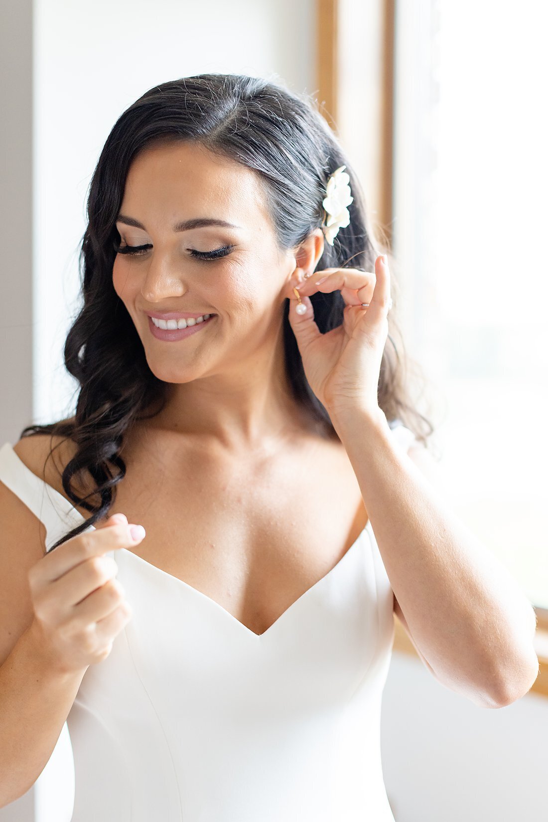 Beautiful-bride-puts-on-earings-while-she-gets-ready-to-go-see-her-groom-on-their-wedding-day