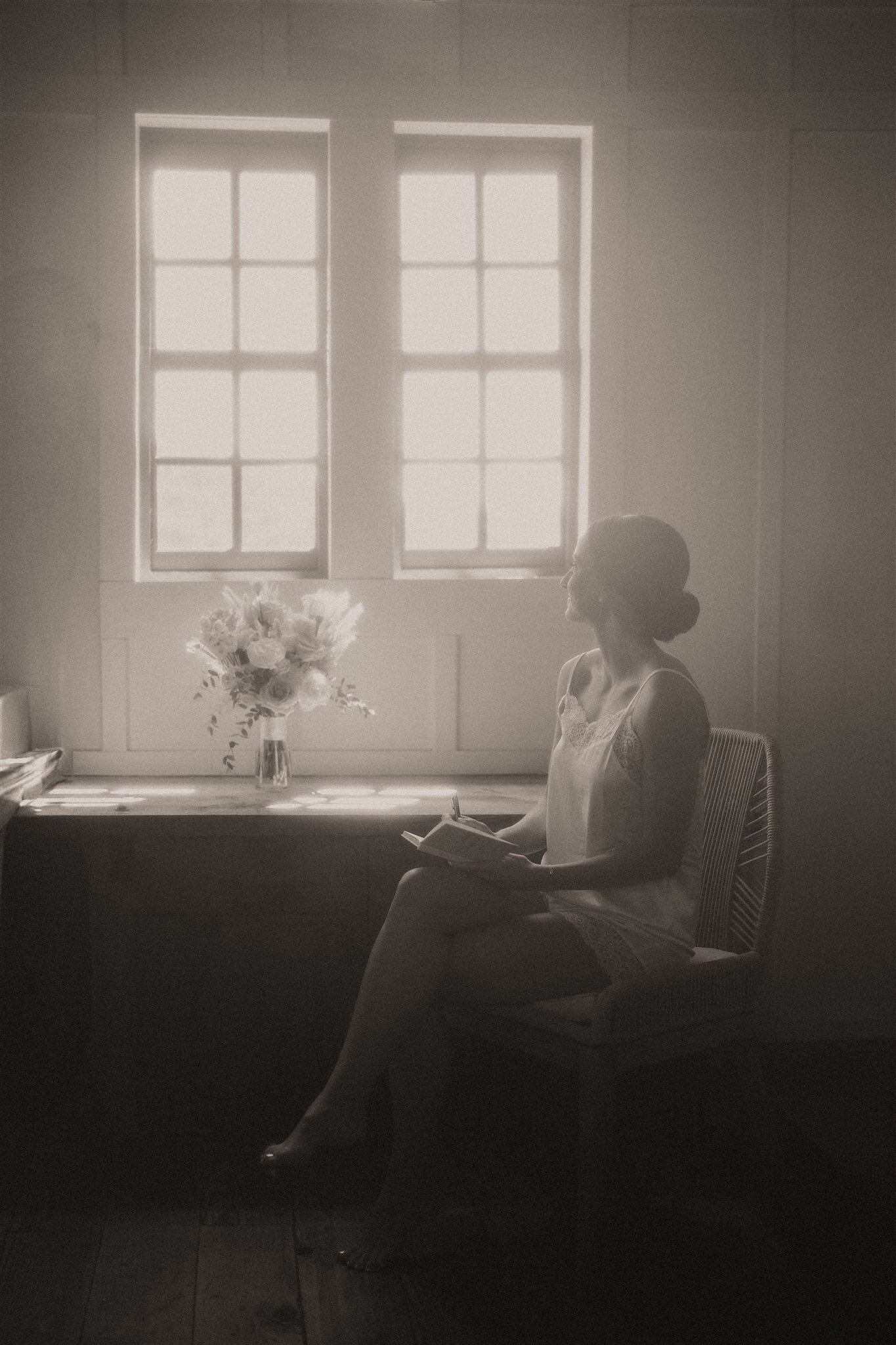 Vintage black and white photo of bride writing vows in bridal suite