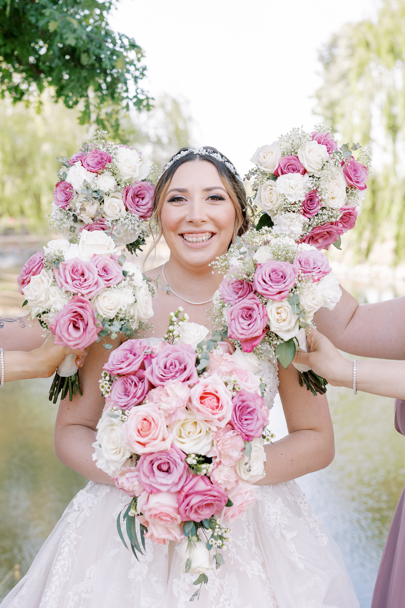 bridal portrait of bride holdin gher pink rose bouquet while her bridesmaids hold their pink bouquets around her face captured by sacramento wedding photographer