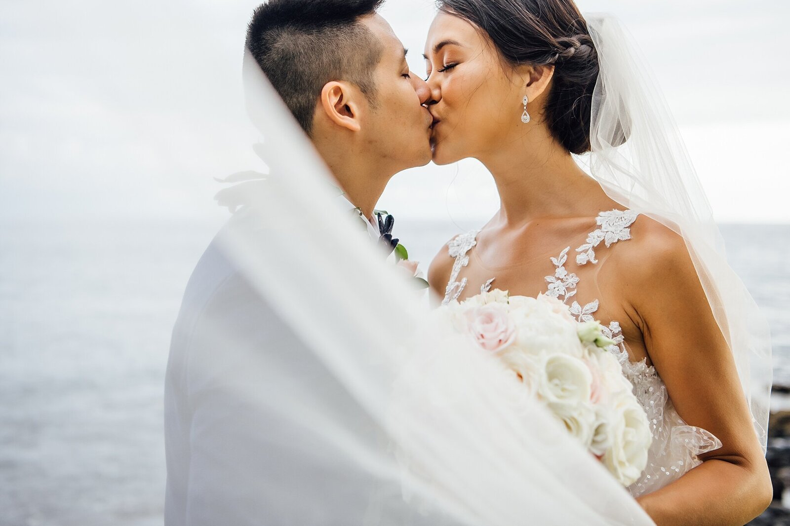 couple kissing during their wedding day at the beach
