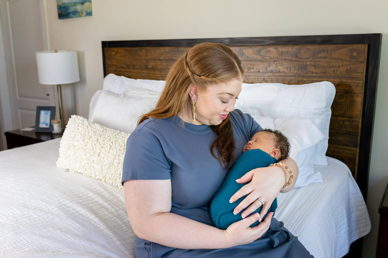 Mom and her newborn sitting on the master bed during their Woodbridge newborn photography session.