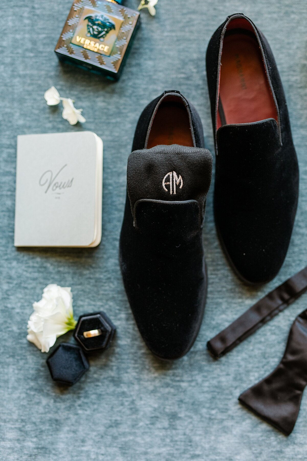 Groom details including suede shoes, cuff links, vow book, and ring with engraved socks at South Coast Winery in Temecula, California.