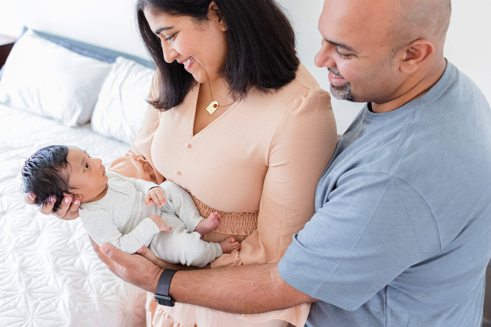 A mom holding her newborn son as dad snuggles them both from the side.