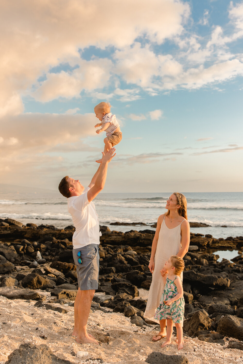 dad tossing baby in air on beach