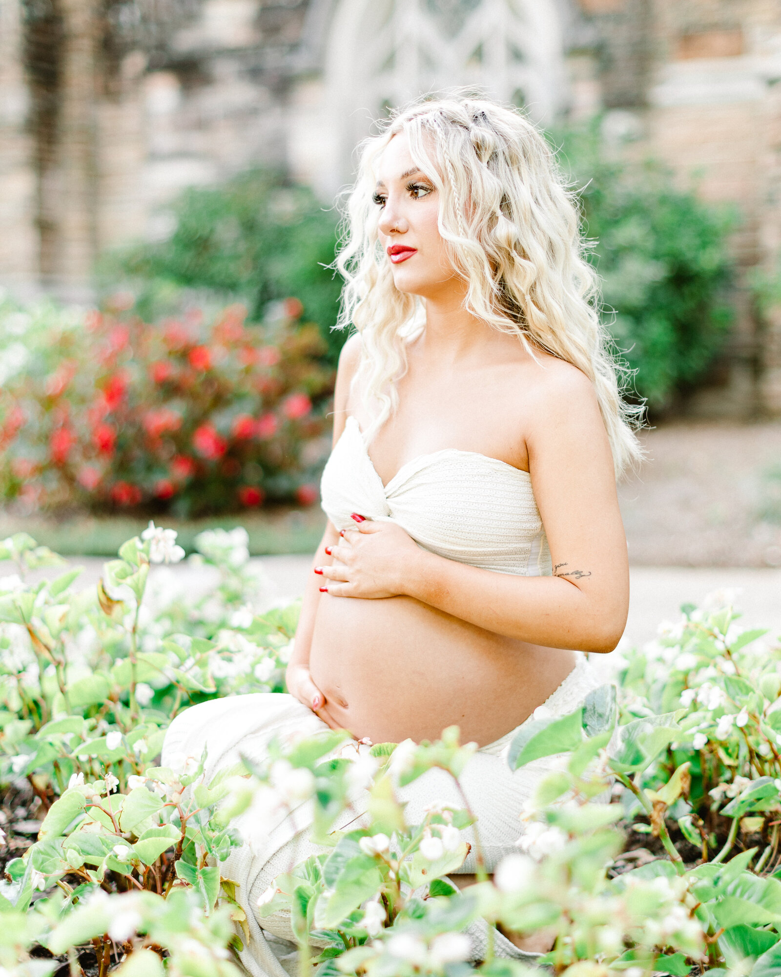 Cassidy seated in a bed of blooming flowers for her maternity session, photographed by Abby Bell Photography in Alabama.