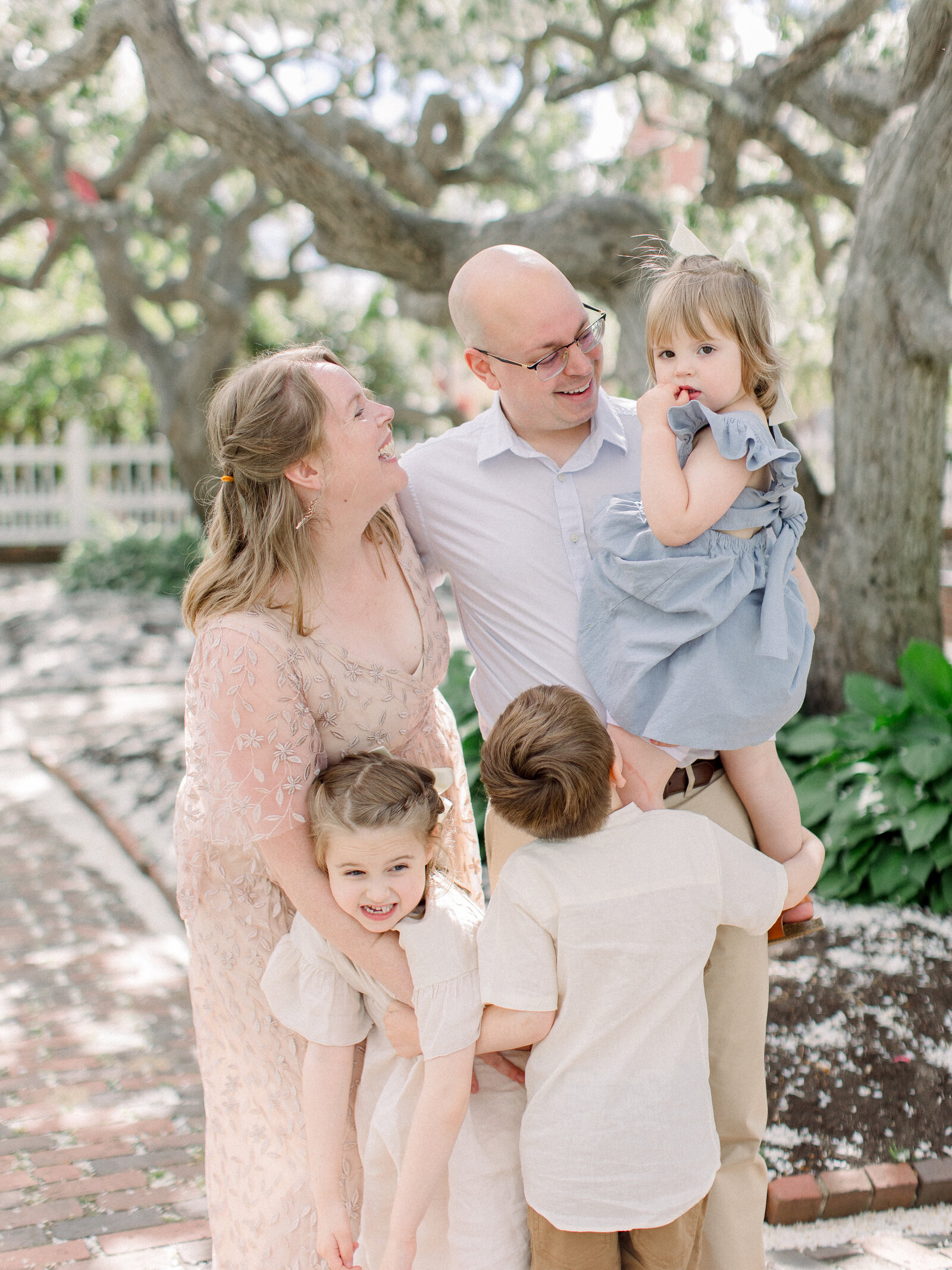 Family of five laughing toghether in a spring garden of flowering cherry trees by NH newborn photographer Fieldstone Studio.